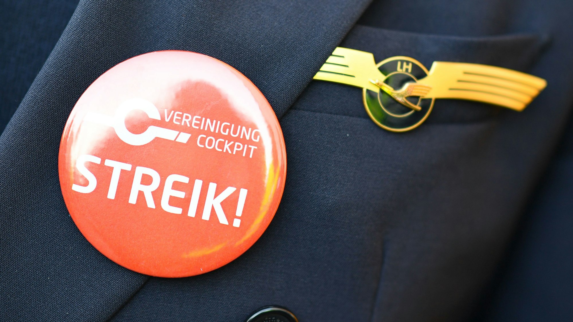 Ein Lufthansa-Pilot trägt bei einer früheren Kundgebung der Pilotengewerkschaft Vereinigung Cockpit einen Button mit der Aufschrift „Streik“ auf seiner Uniform. (Archivbild)