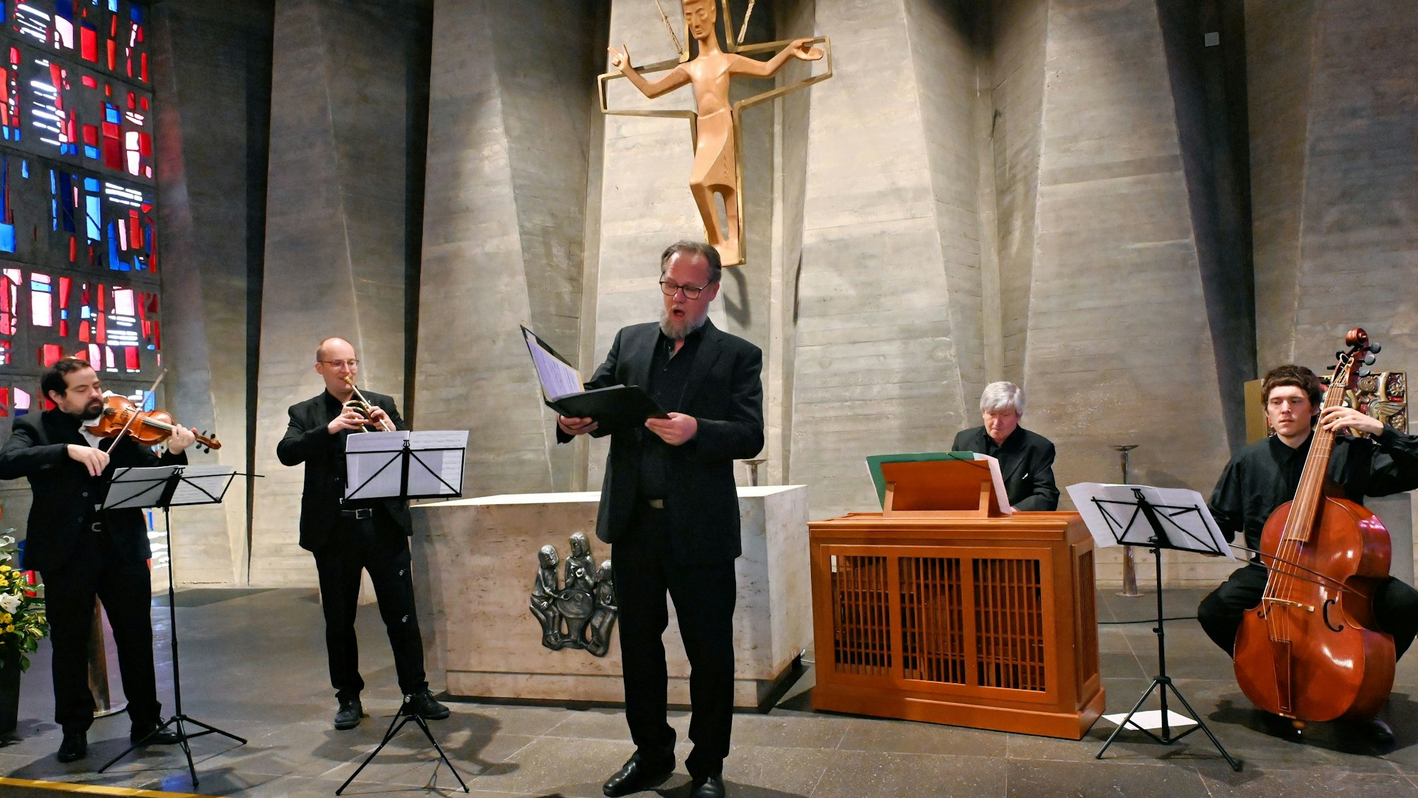Bass-Bariton Thomas Bonni steht singend im Altarraum der Kapelle. Neben ihm stehen und sitzen vier Musiker, die ihn begleiten.