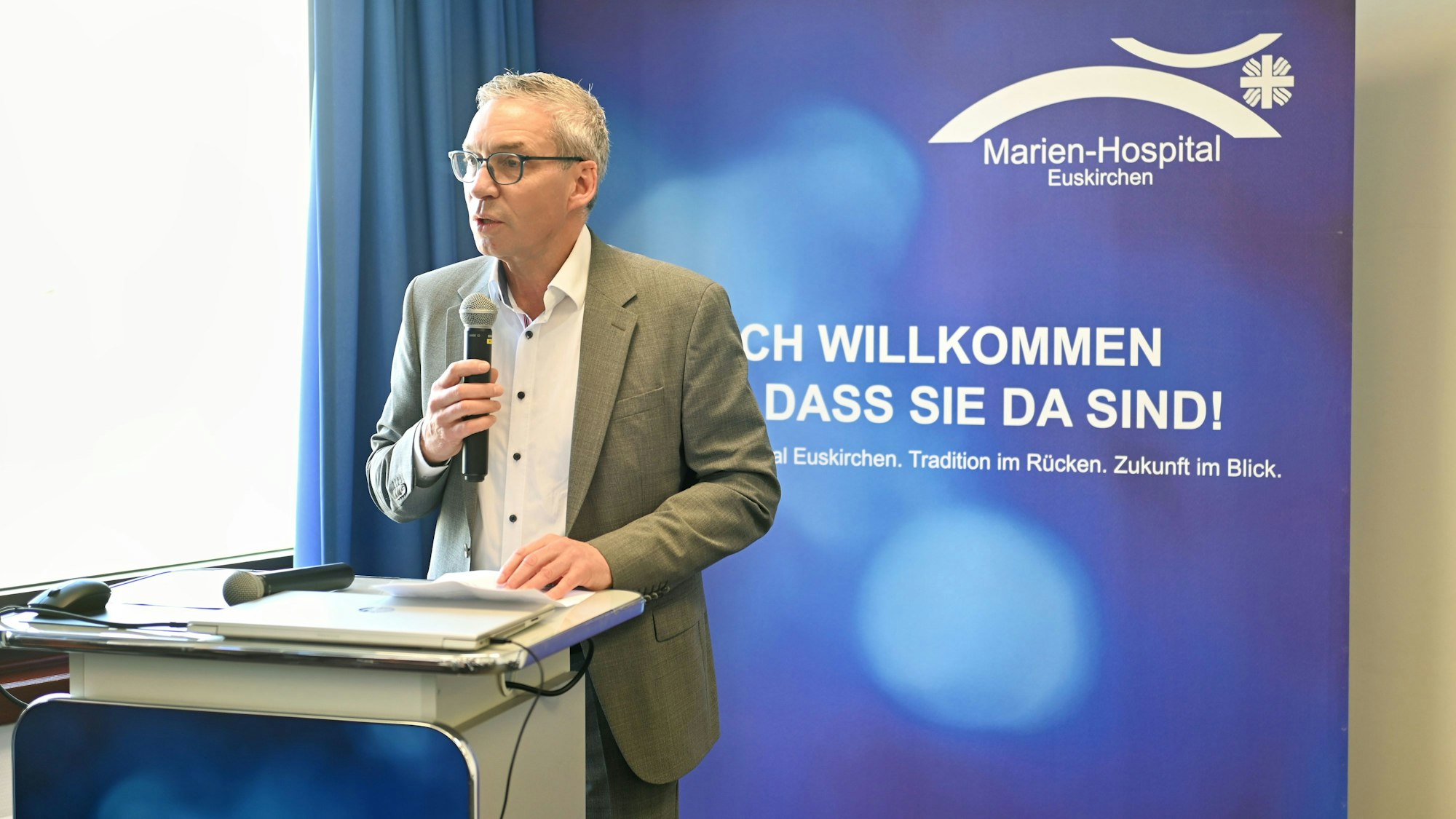 Geschäftsführer Wolfgang Schneidersteht am Rednerpult und spricht in das Mikrophon.