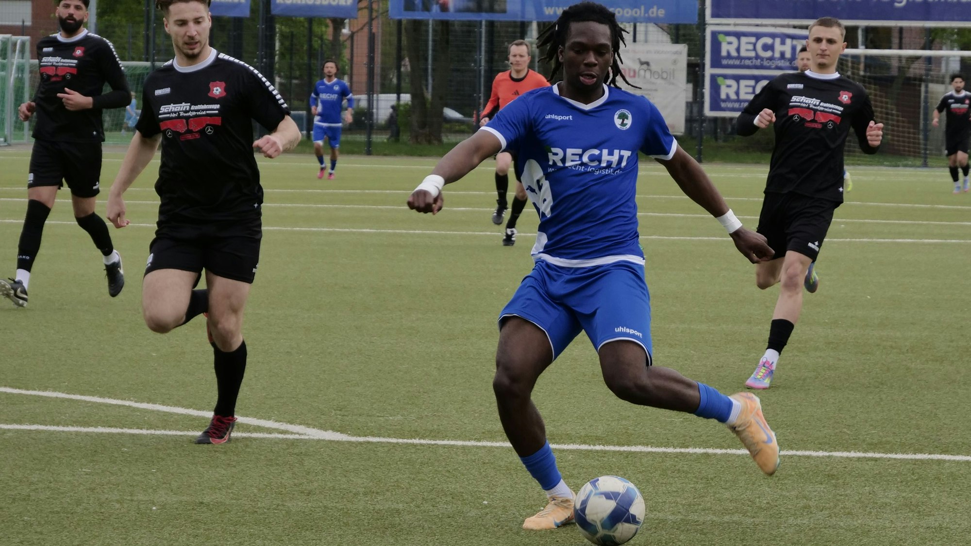 Das Foto zeigt einen Fußballer im blauen Trikot, der mit dem Ball am Fuß auf das Tor zu rennt.