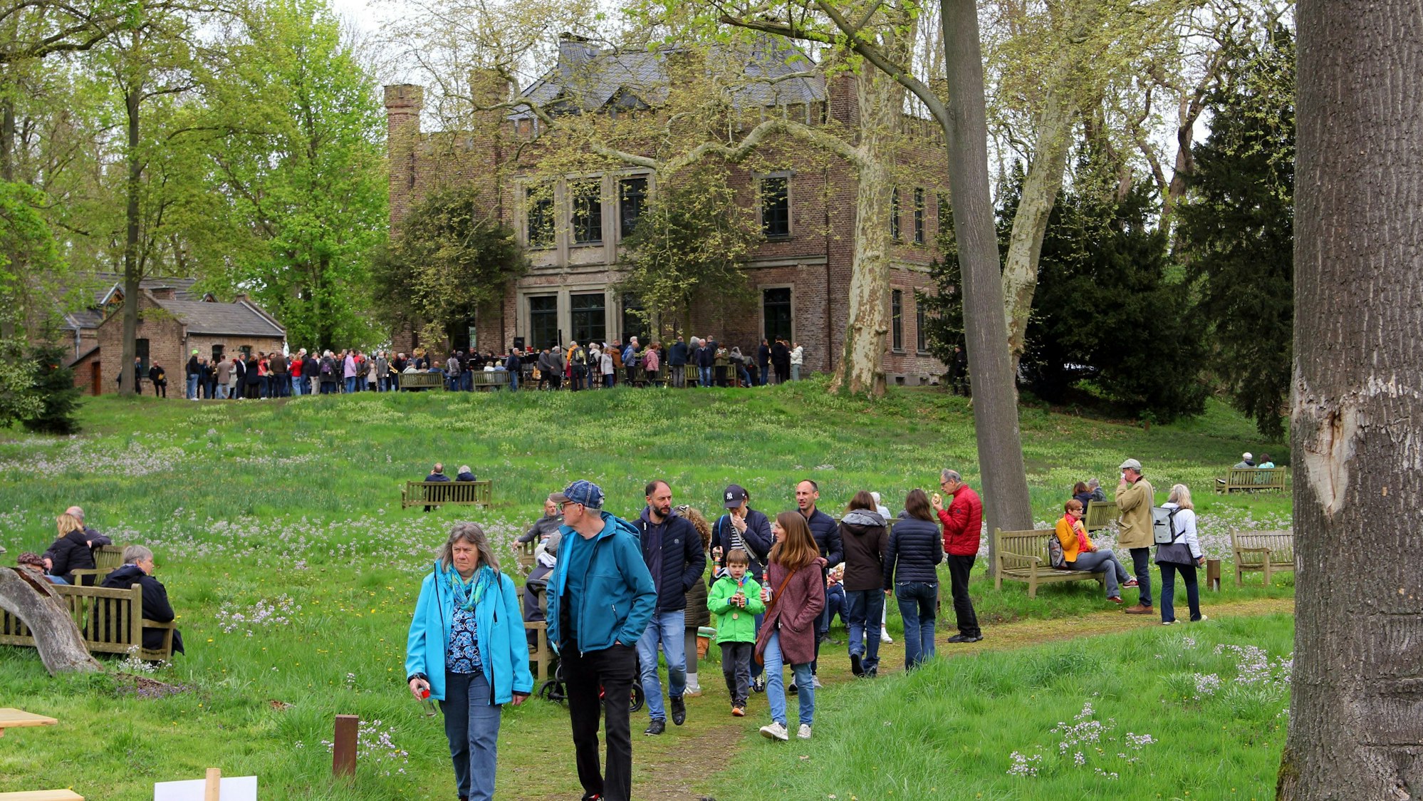 Das Foto zeigt Menschen im Garten eines Ritterguts.