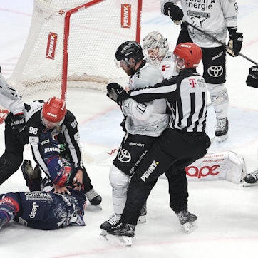 Referees schützen Berlins Ty Ronning nach Zweikampf mit Kölns Torwart Janne Juvonen.