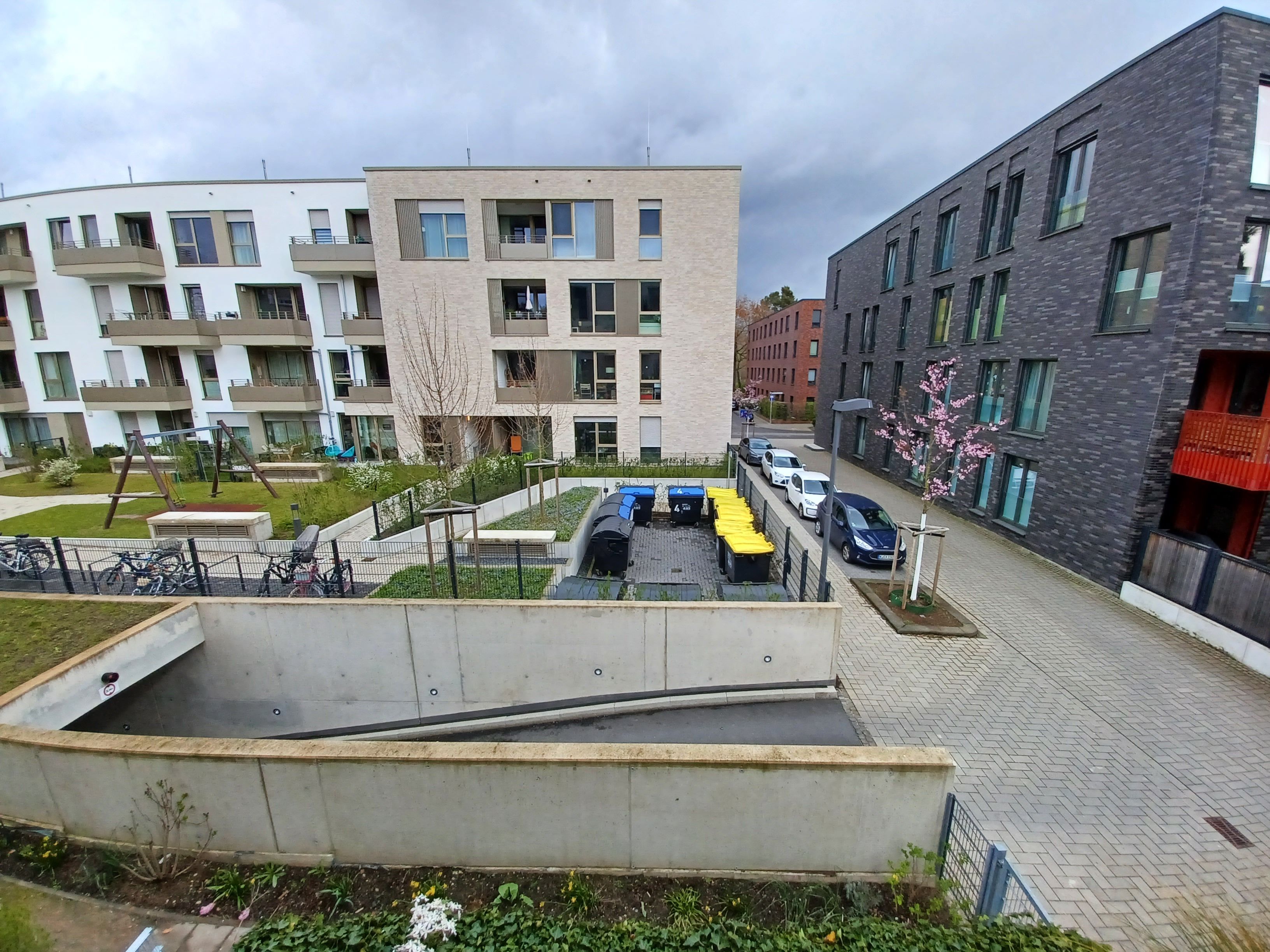 Auf einer Freifläche stehen die 13 Gemeinschafts-Müllcontainer der 2024 eröffneten Wohnanlage.