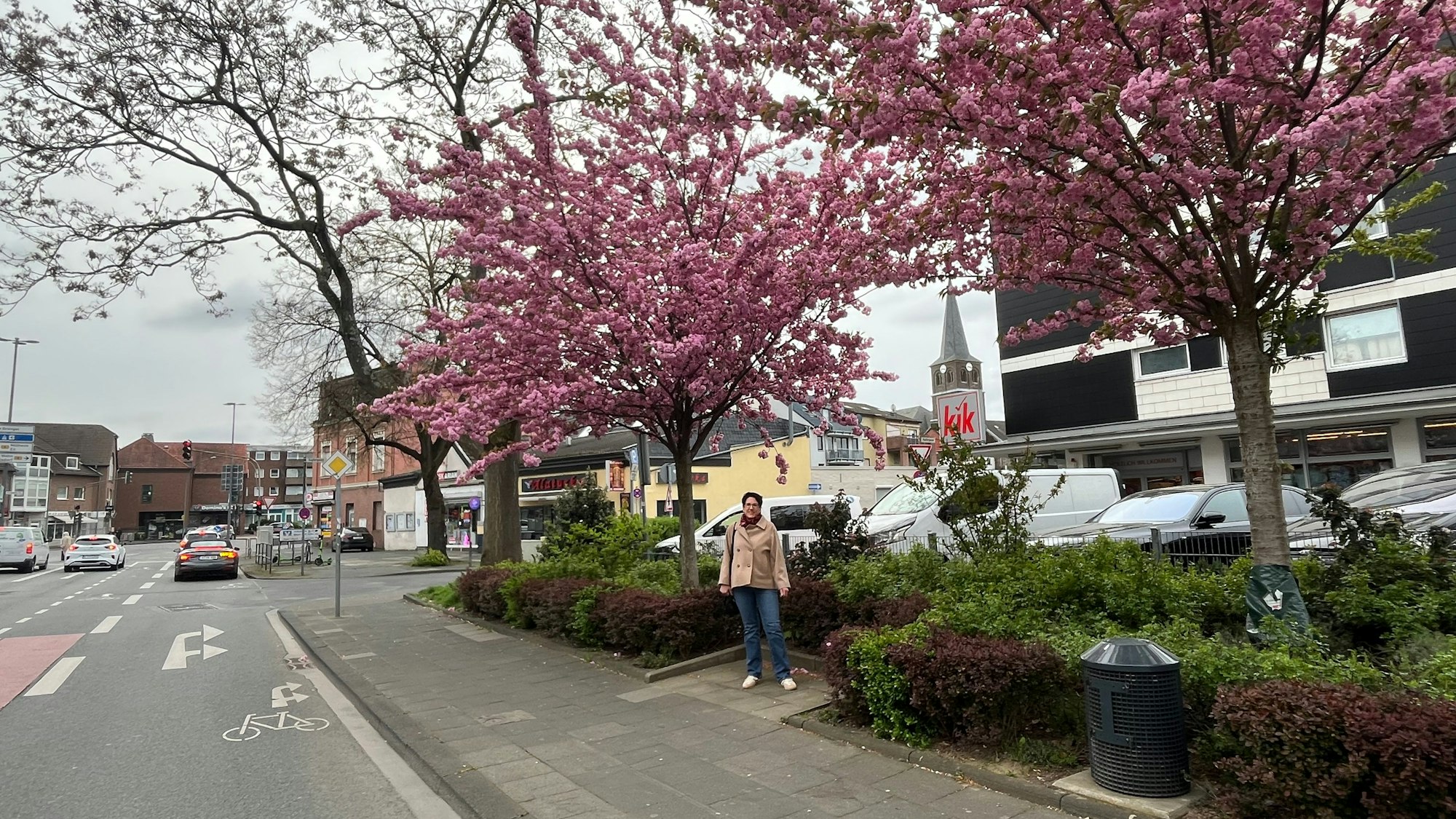 Eine Frau steht in einer gepflasterten Nische des vom Bürgerverein gepflegten Beetes an der Kaiserstraße in Urbach.