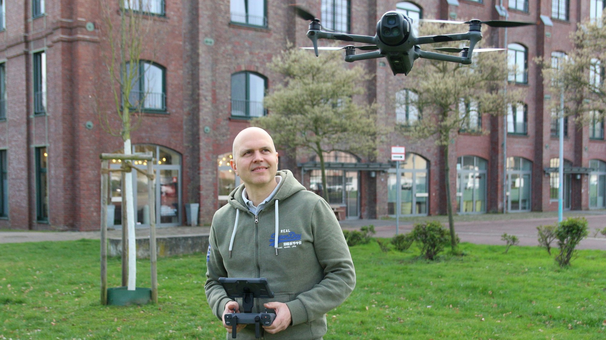Auf dem Bild ist ein Mann mit einer Drohne und einer Fernsteuerung zu sehen.
