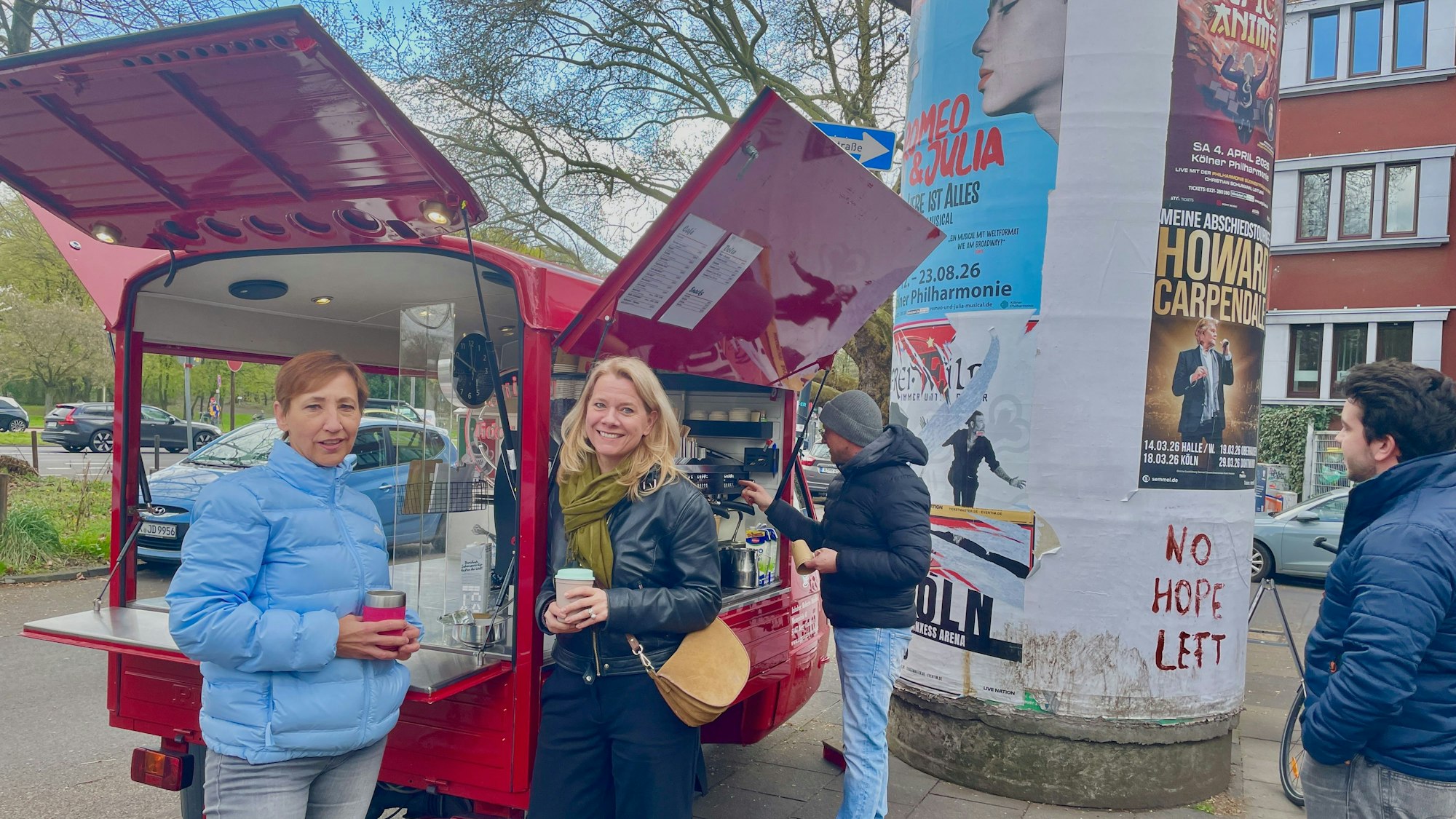 Zwei Frauen stehen mit Kaffee to go an einem roten Kaffeemobil.