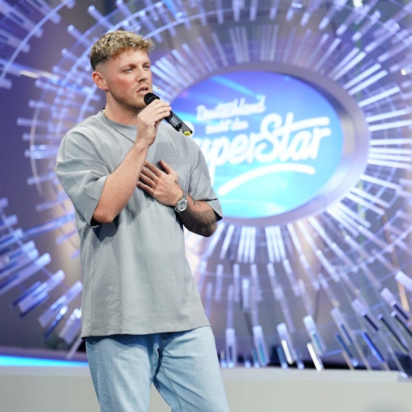 Maric Verch bei seinem Auftritt. Er hält ein Mikro in der Hand und steht vor dem DSDS-Logo.