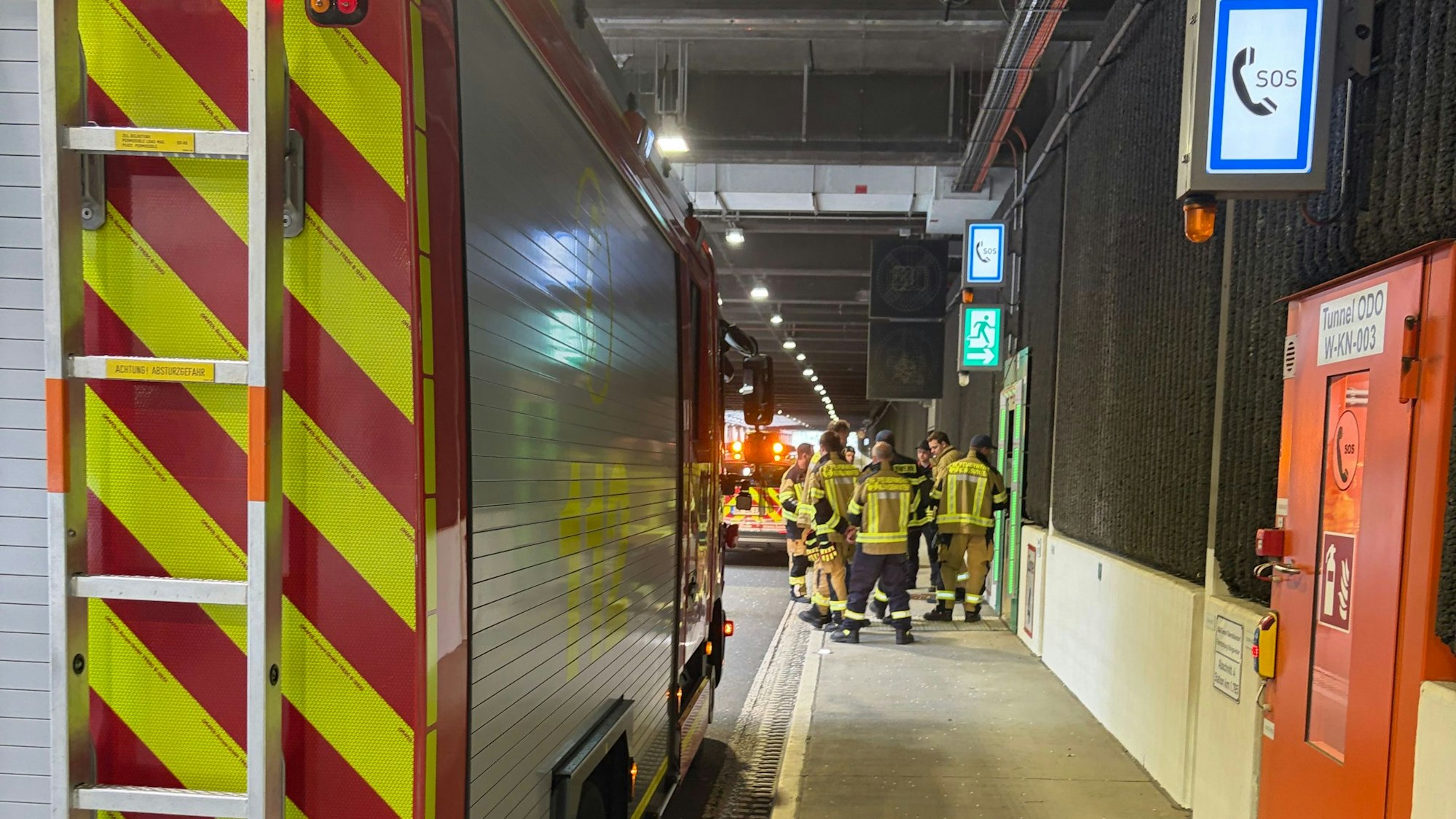 Ein Feuerwehrfahrzeug und Feuerwehrleute in einem Tunnel.