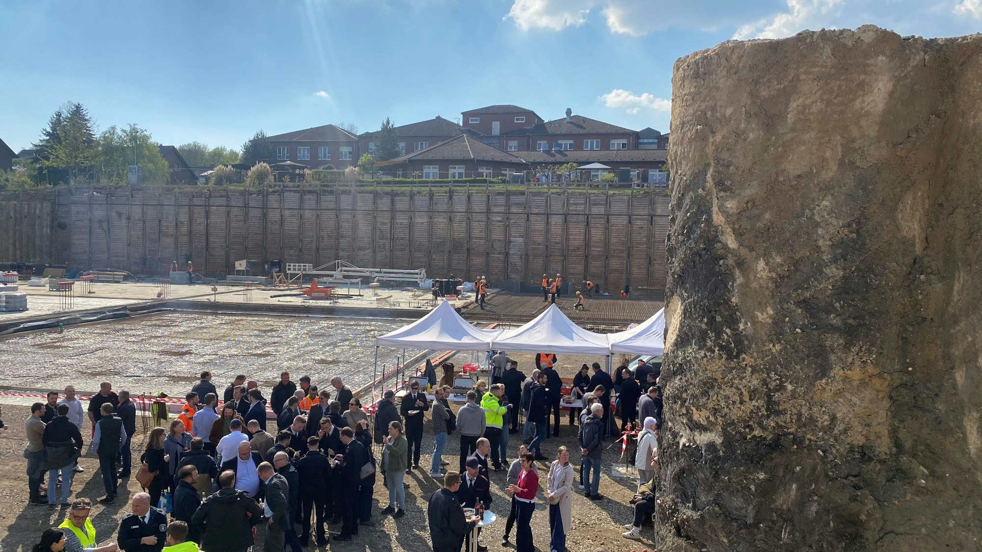 Zu sehen ist die anlässlich der Grundsteinlegung von vielen Menschen besuchte Baugrube.