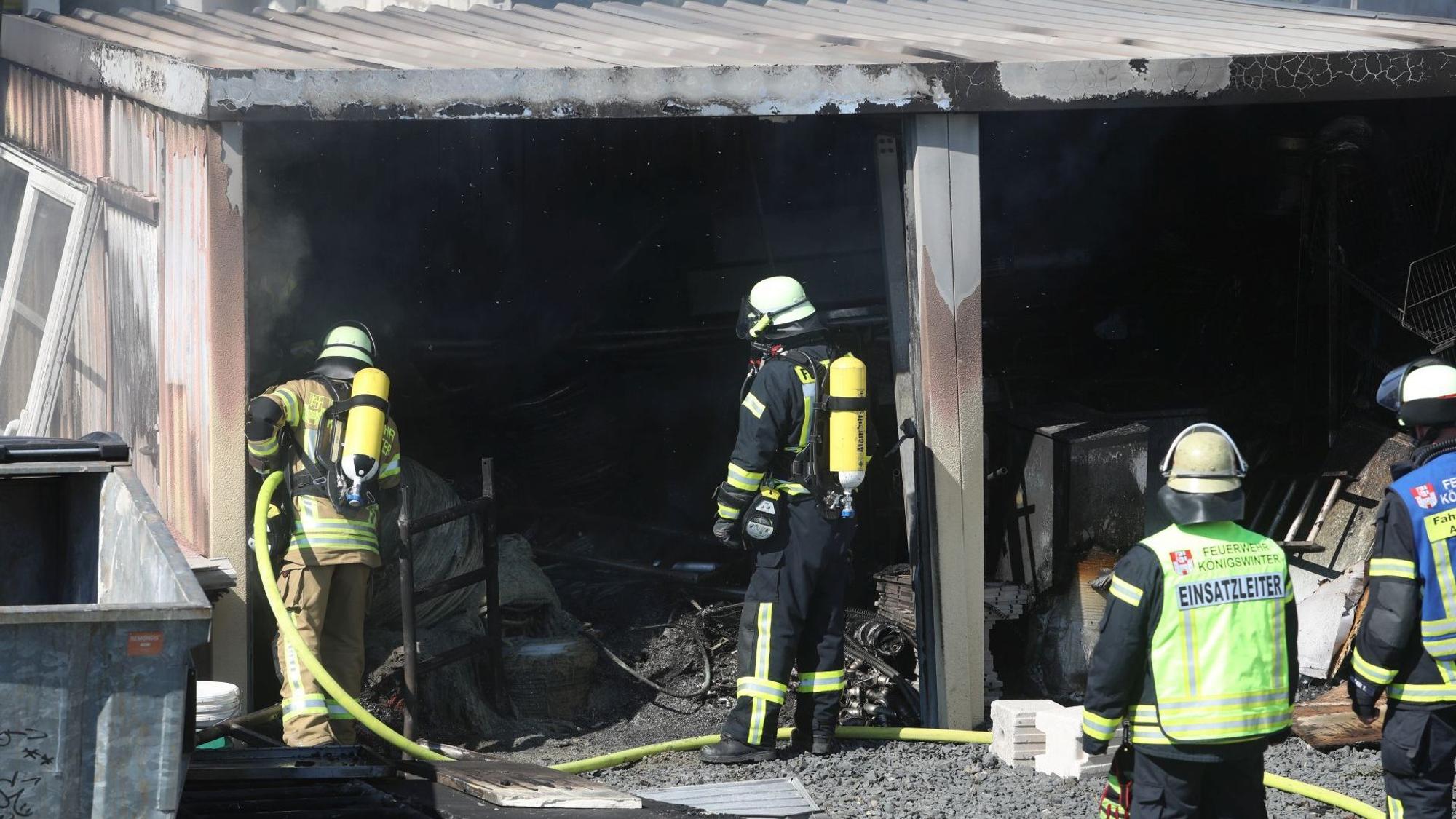 Feuerwehrleute vor ausgebrannten Garagen.