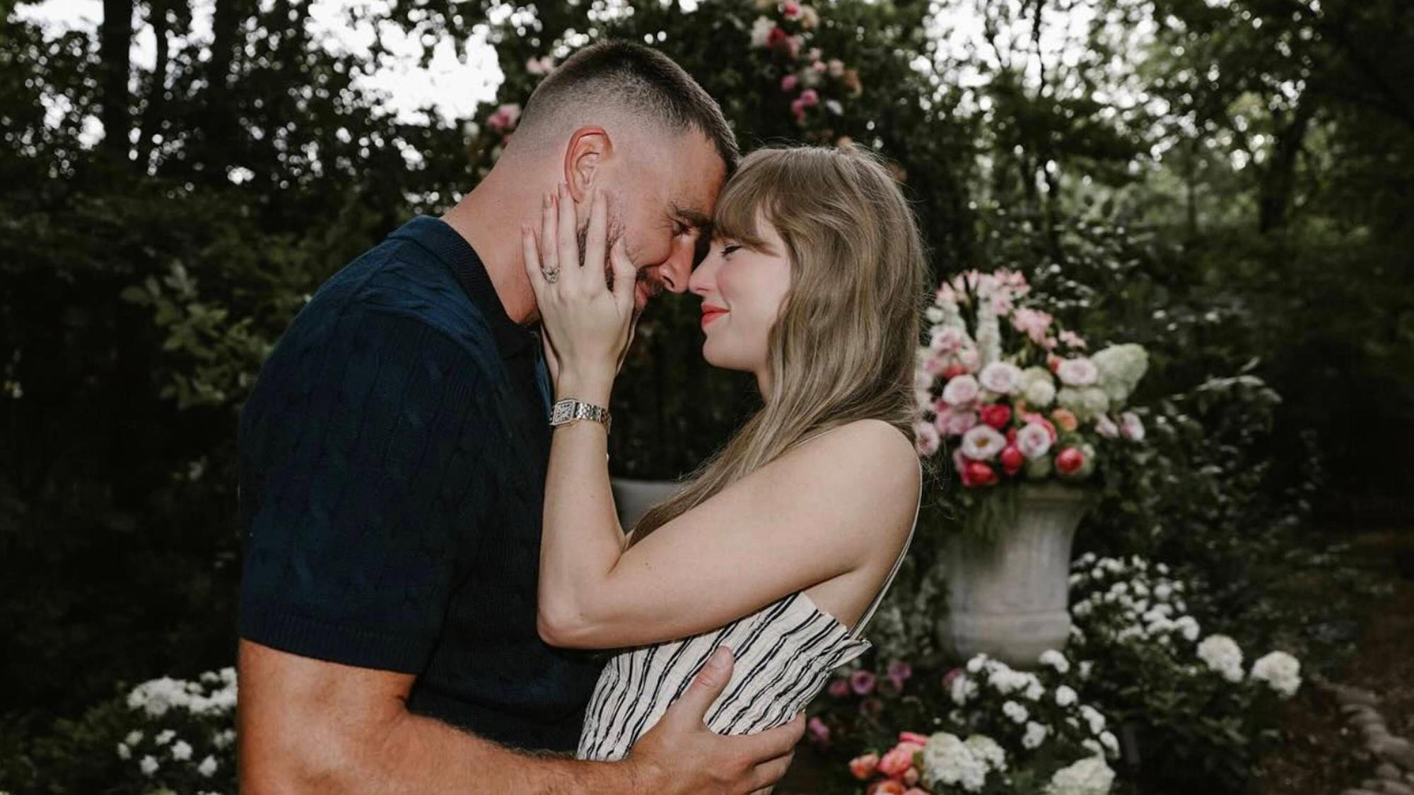 Travis Kelce und Taylor Swift umarmen sich vor einem Blumengesteck.