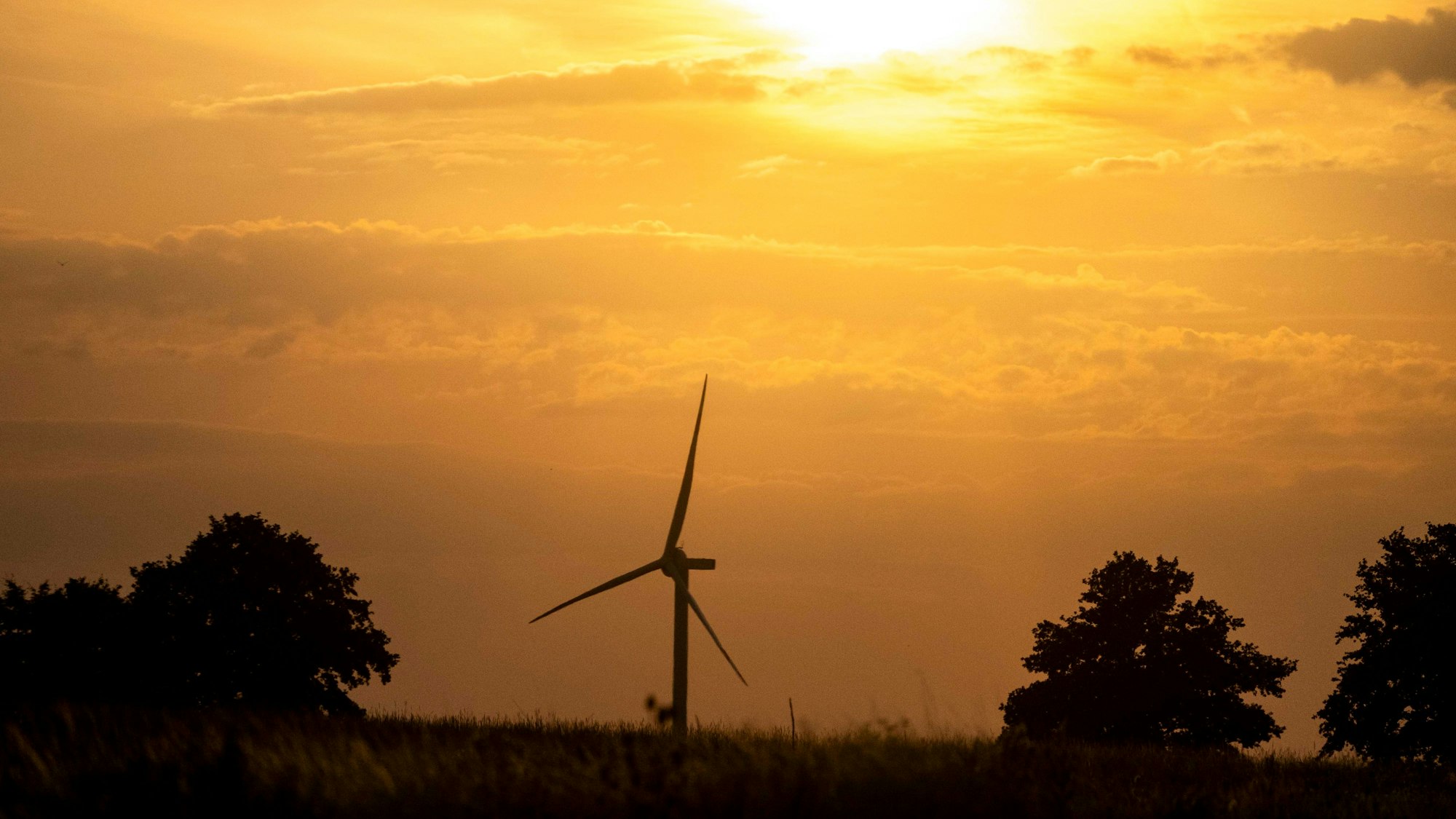 Das Bild zeigt ein Windrad im Sonnenuntergang.