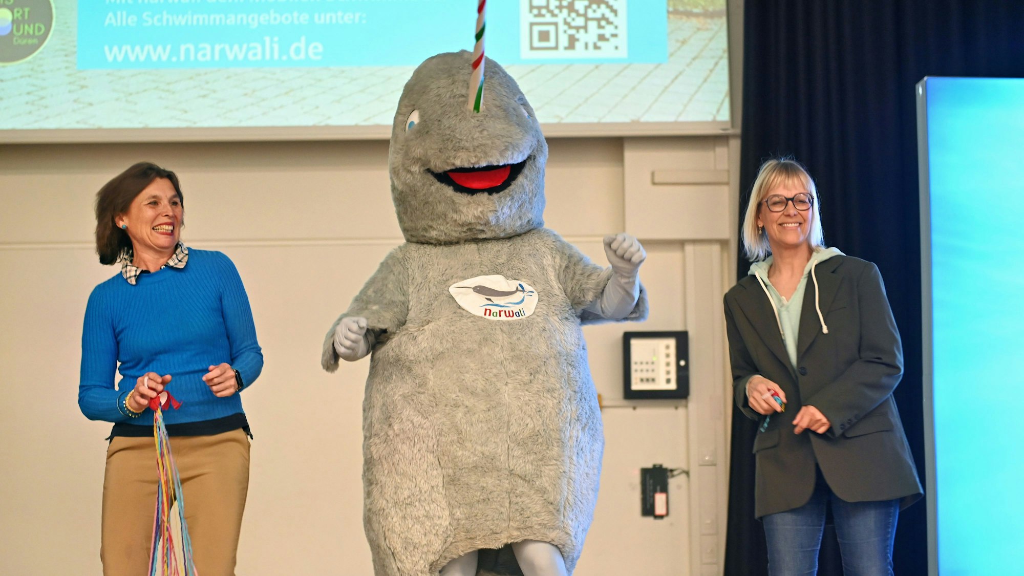 Die beiden Frauen stehen neben einer Person in einem Walkostüm.
