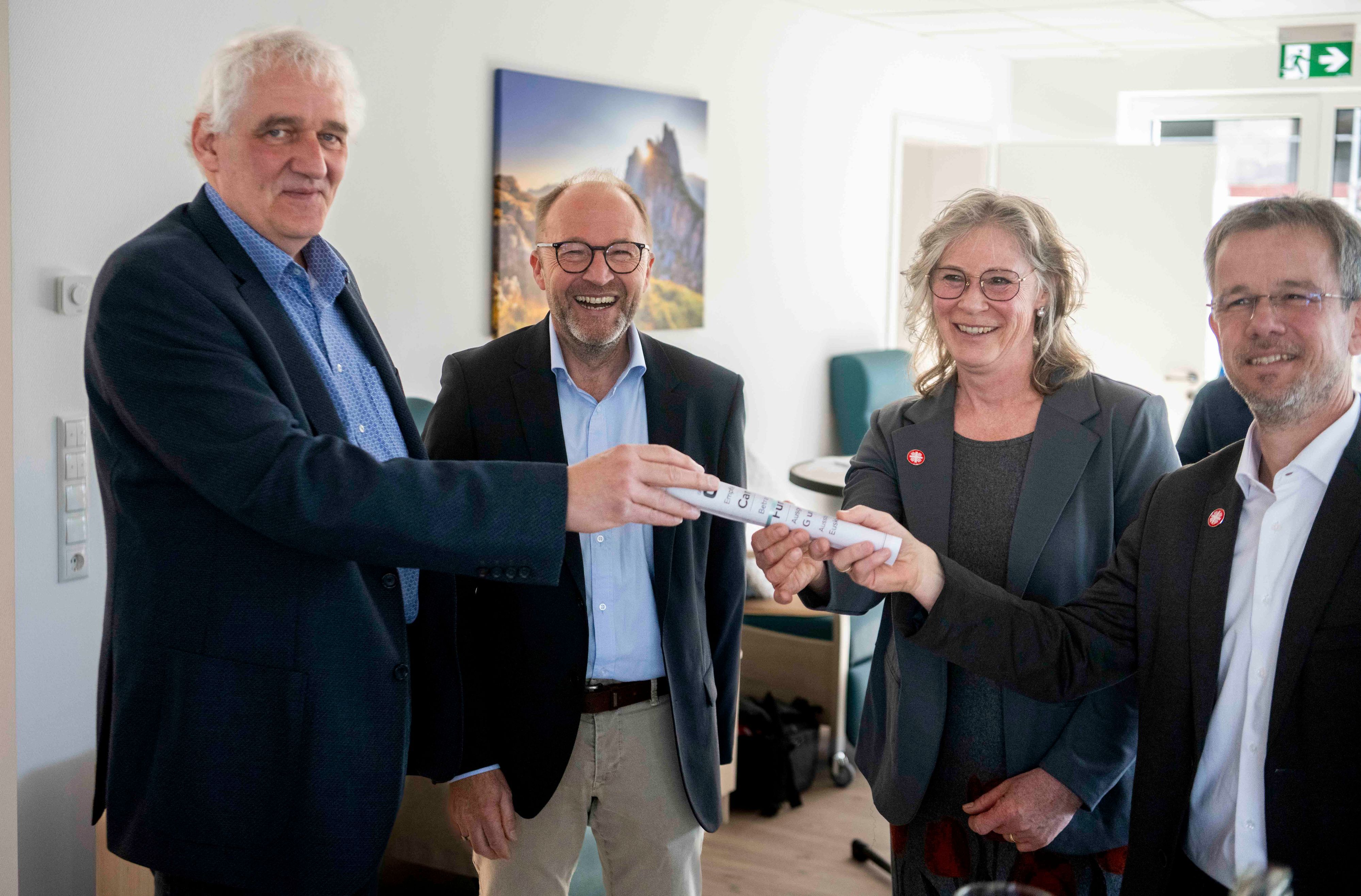 Zwei Vertreter der Firma G&S überreichen die Spende an die beiden Caritasvorstände.