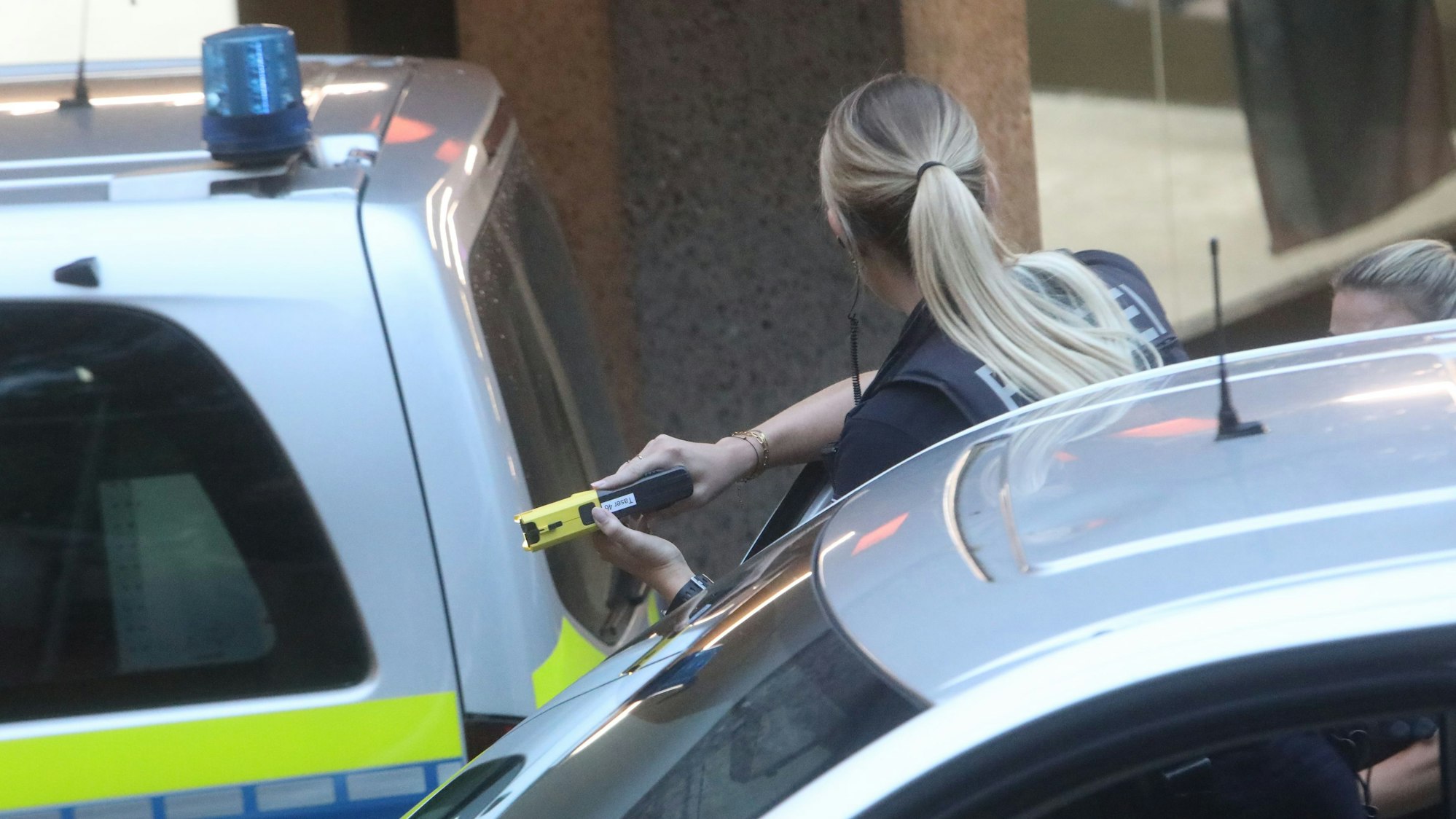 Eine Polizistin zwischen Polizeiautos