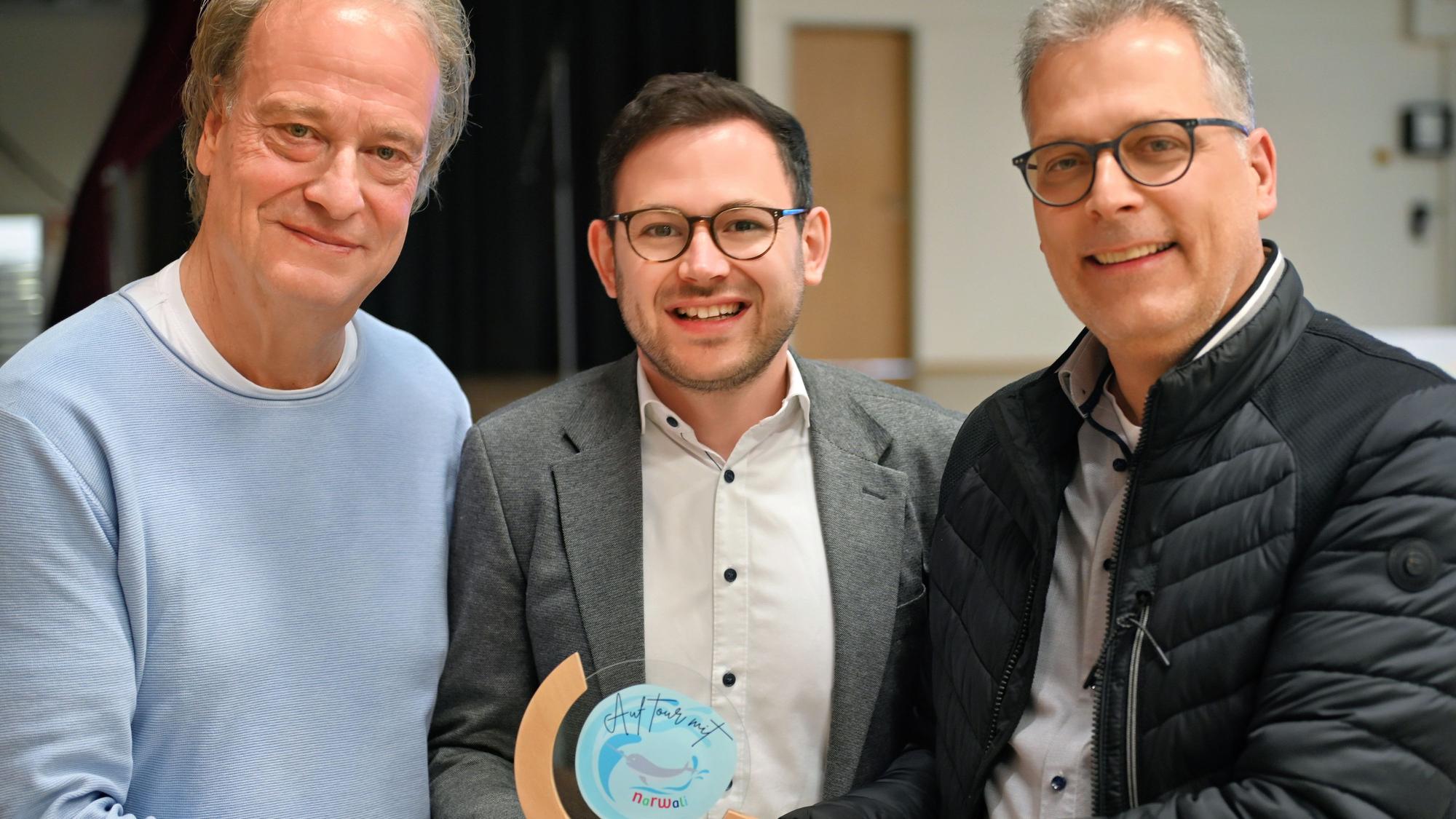 Die drei Männer stehen nebeneinander und präsentieren den Narwali-Pokal.