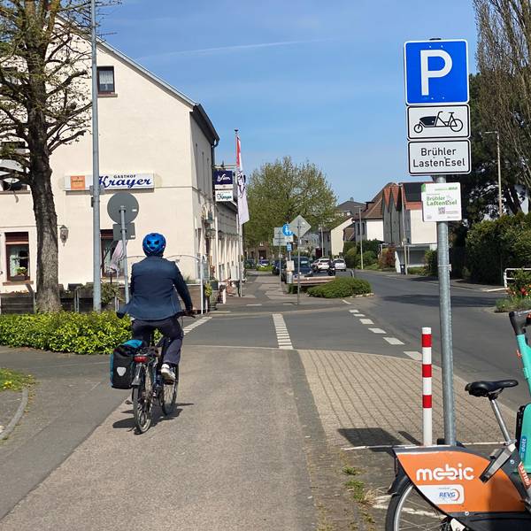 Zu sehen ist ein Radler, der entlang einer Straße fährt.