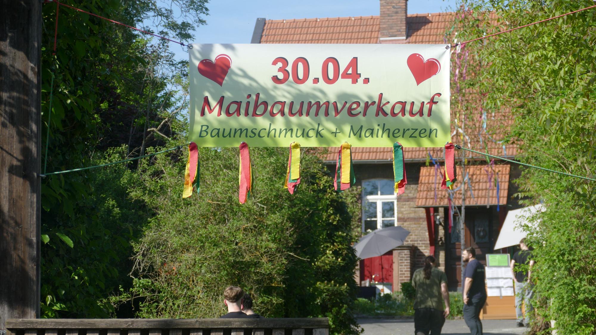 Ein Werbetransparent für den Verkauf von Maibäumen.