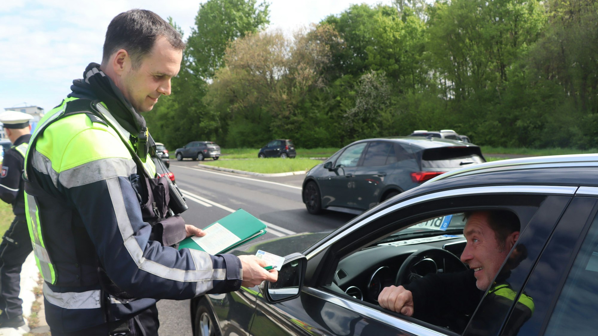 Ein Polizist kontrolliert einen Autofahrer.