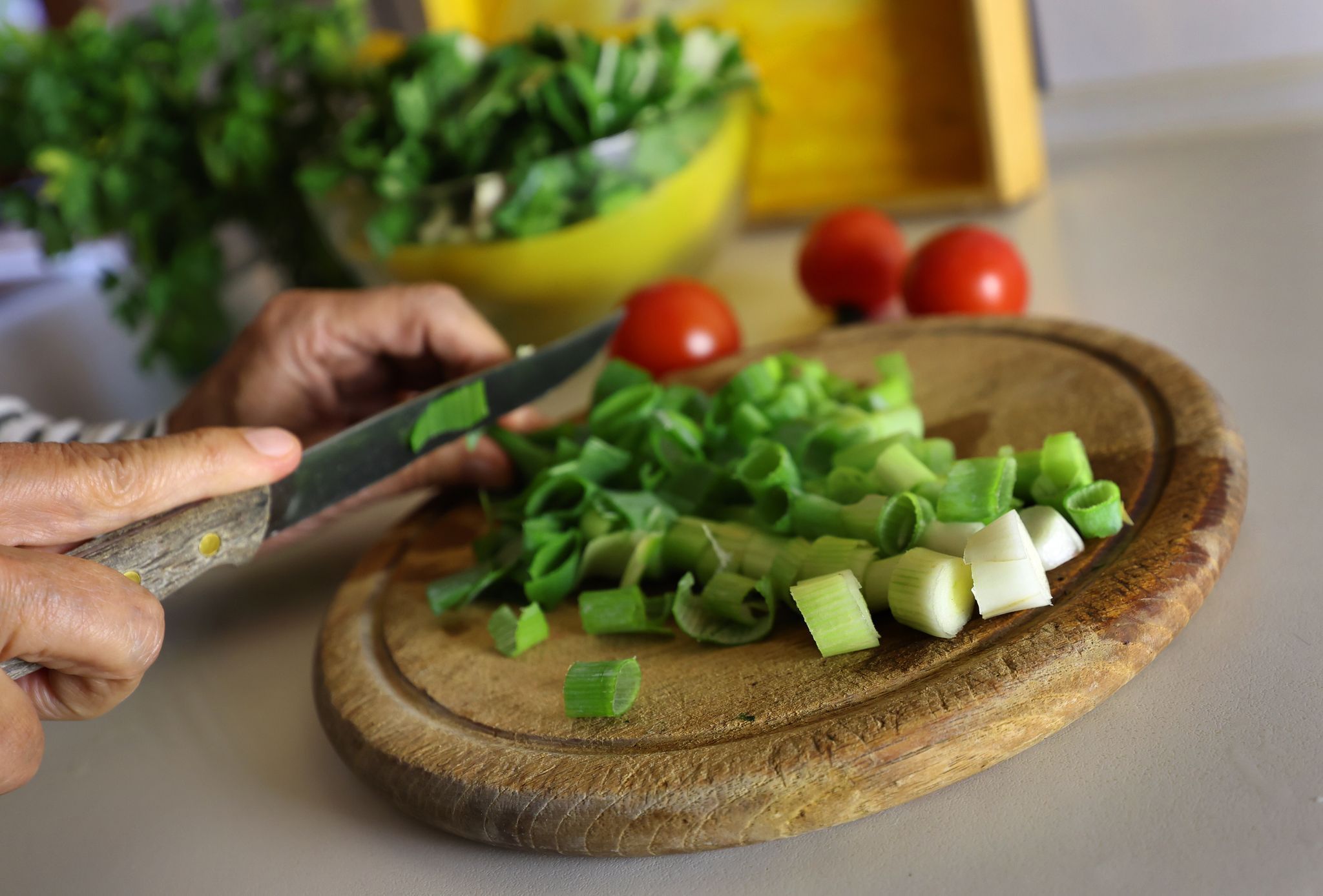 Eine Frau schneidet beim Kochen Lauchzwiebeln