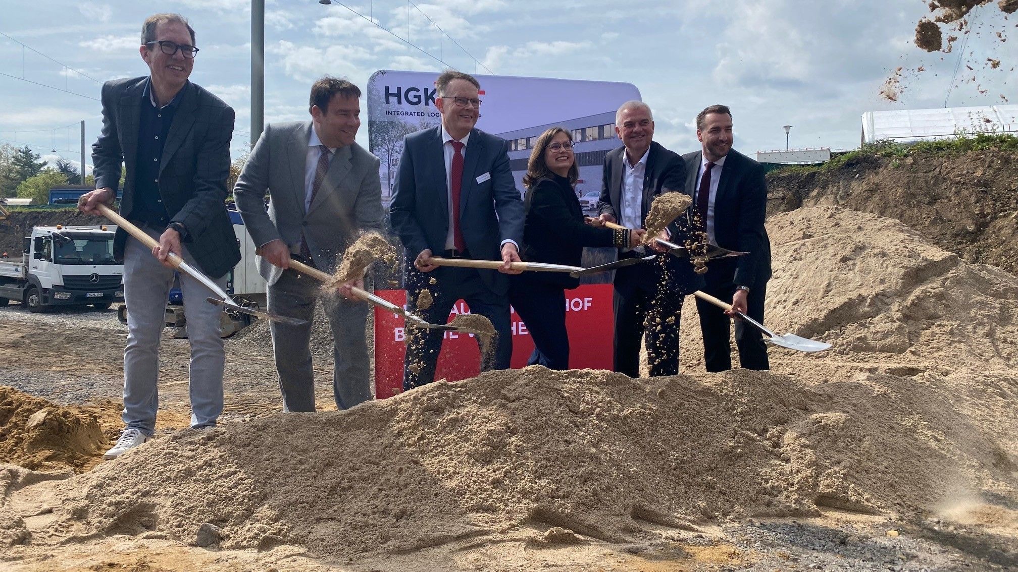 Zu sehen ist eine Gruppe von Menschen, die Spaten in den Händen halten.