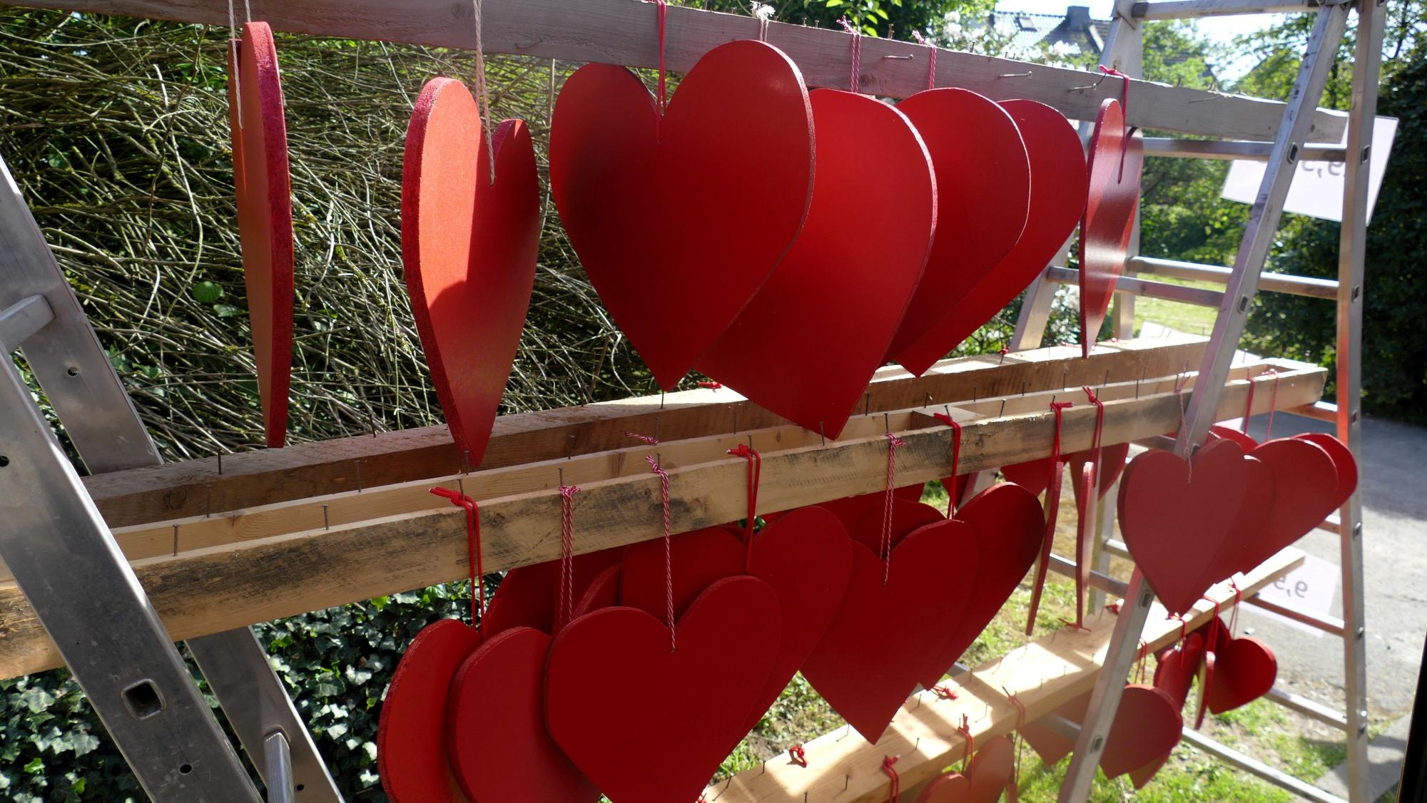 Rote Herzen aus Sperrholz hängen an einem Verkaufsgestell.
