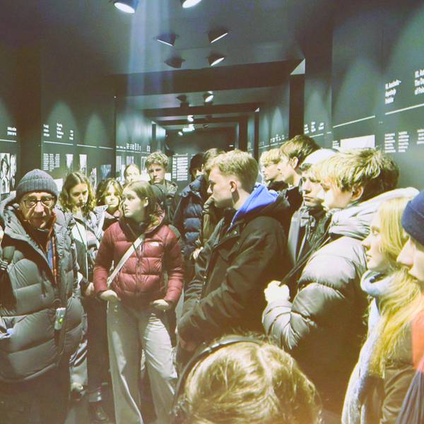 Schüler stehen vor einer Wand mit Schwarz-Weiß-Fotos.