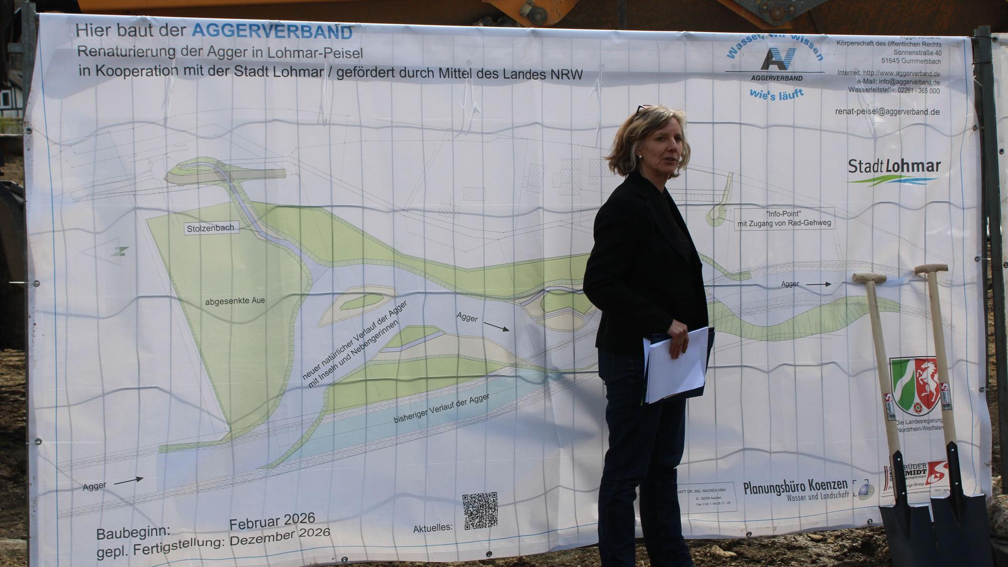 Eine Frau steht vor einem Plakat.