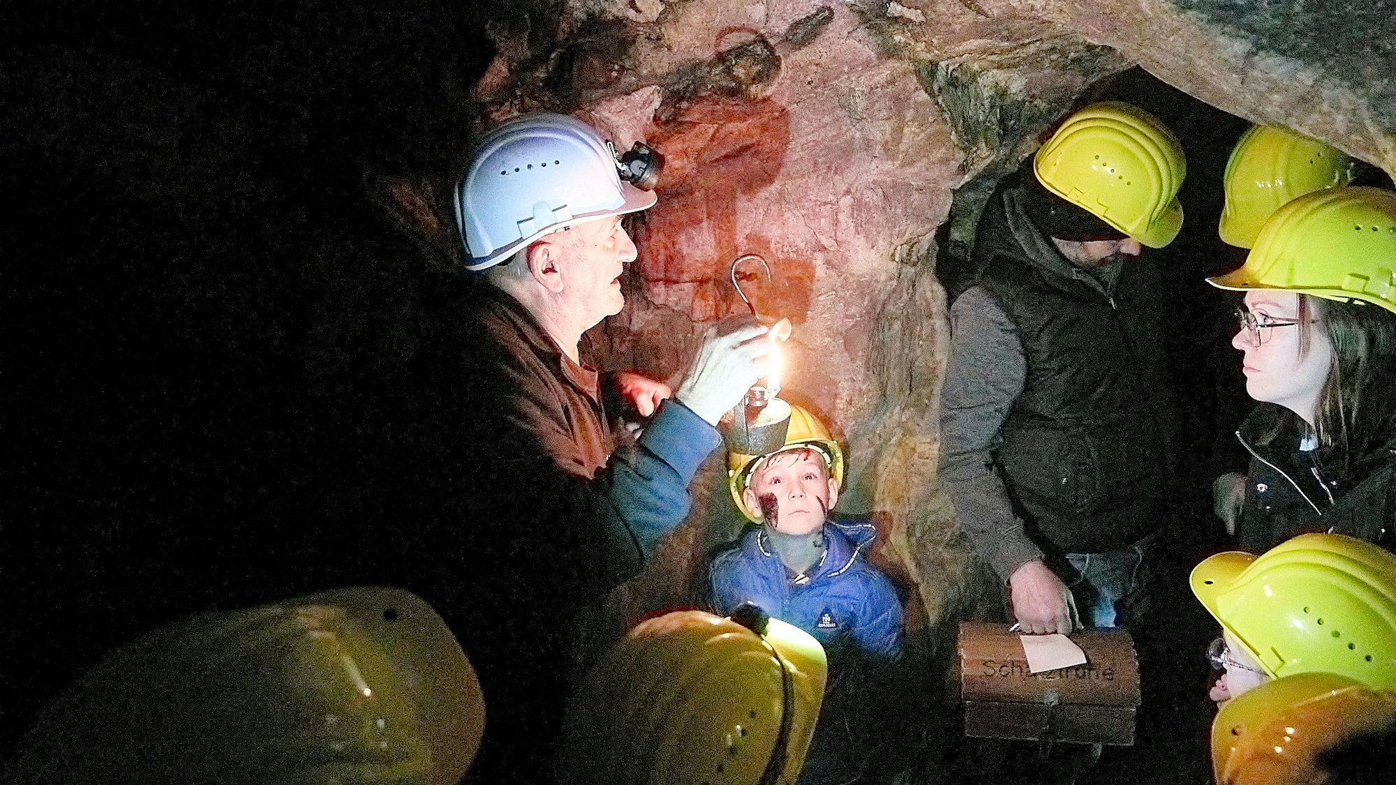 Besucher des Bergwerks Grube Günnersdorf tragen bei einem Unter-Tage-Rundgang Schutzhelme.