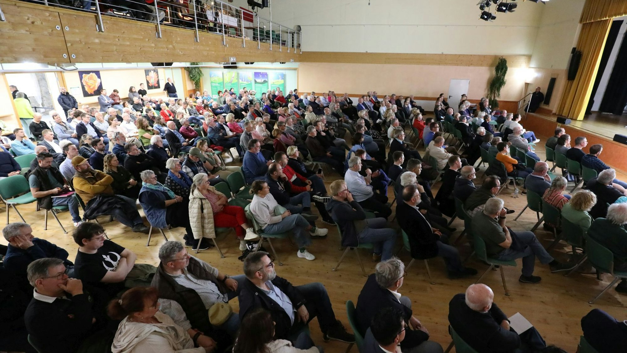 Viele Menschen auf Stühlen in einem großen Saal.