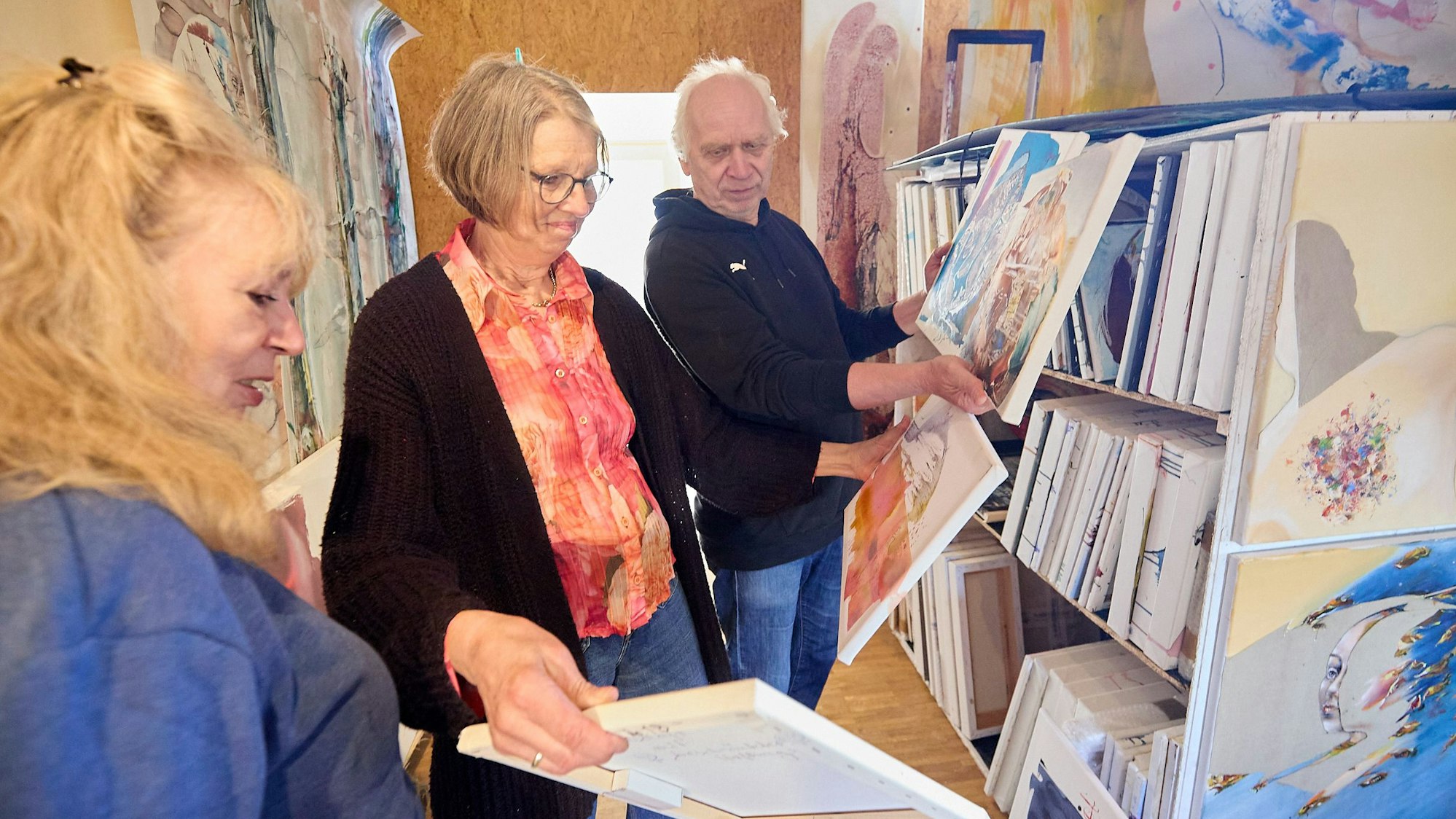 Gundolf und Marianne Roy und Maf Räderscheidt (v.r.n.l.) schauen sich in einem Atelier Gemälde an.