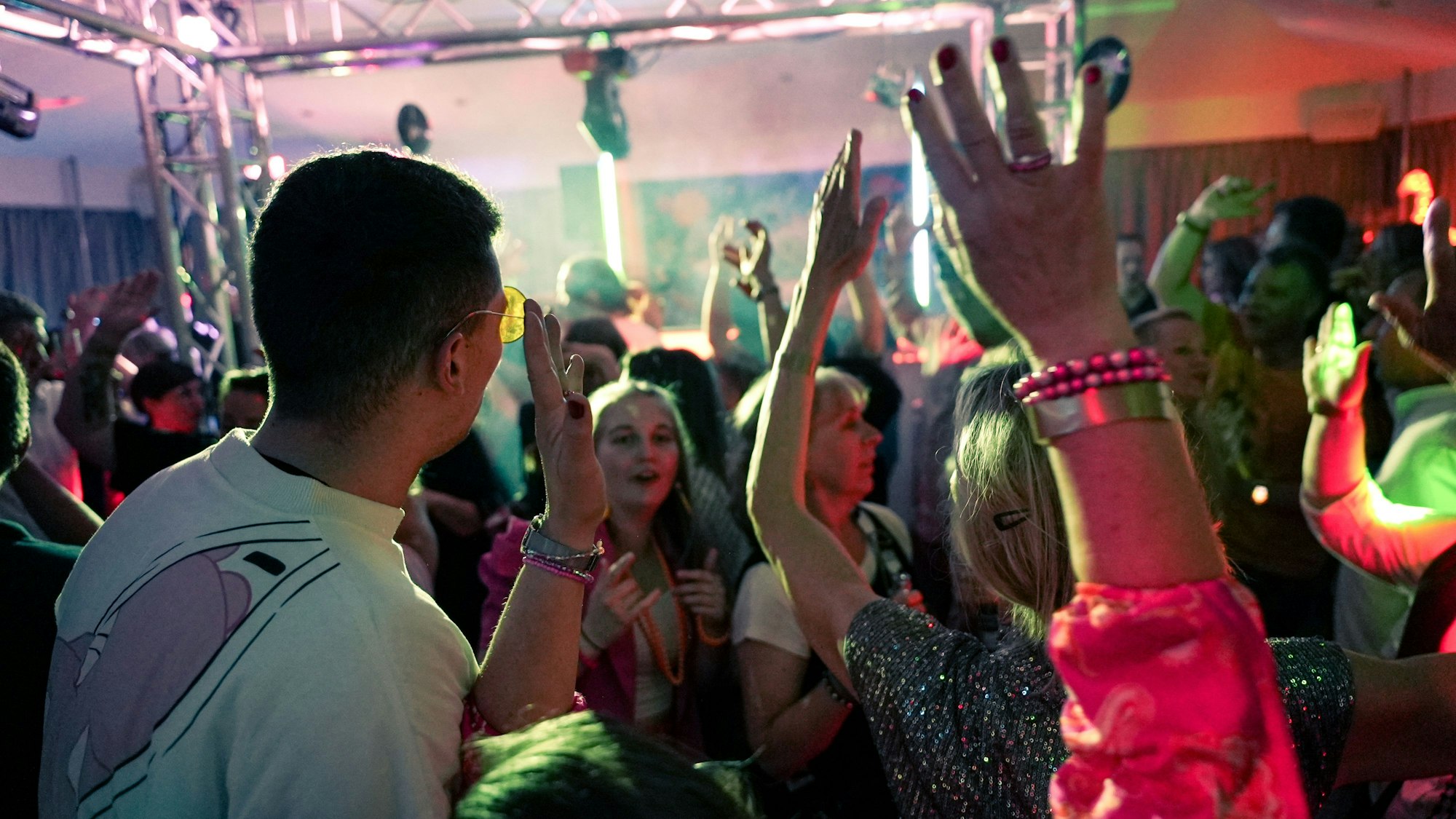 Die Aufnahme zeigt Feiernde in Anziehsachen aus den 1980ern und 1990ern.