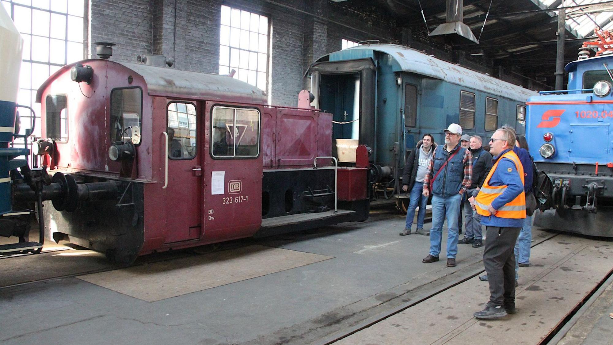 Ein Gruppe Menschen steht an einem alten Eisenbahnwaggong.