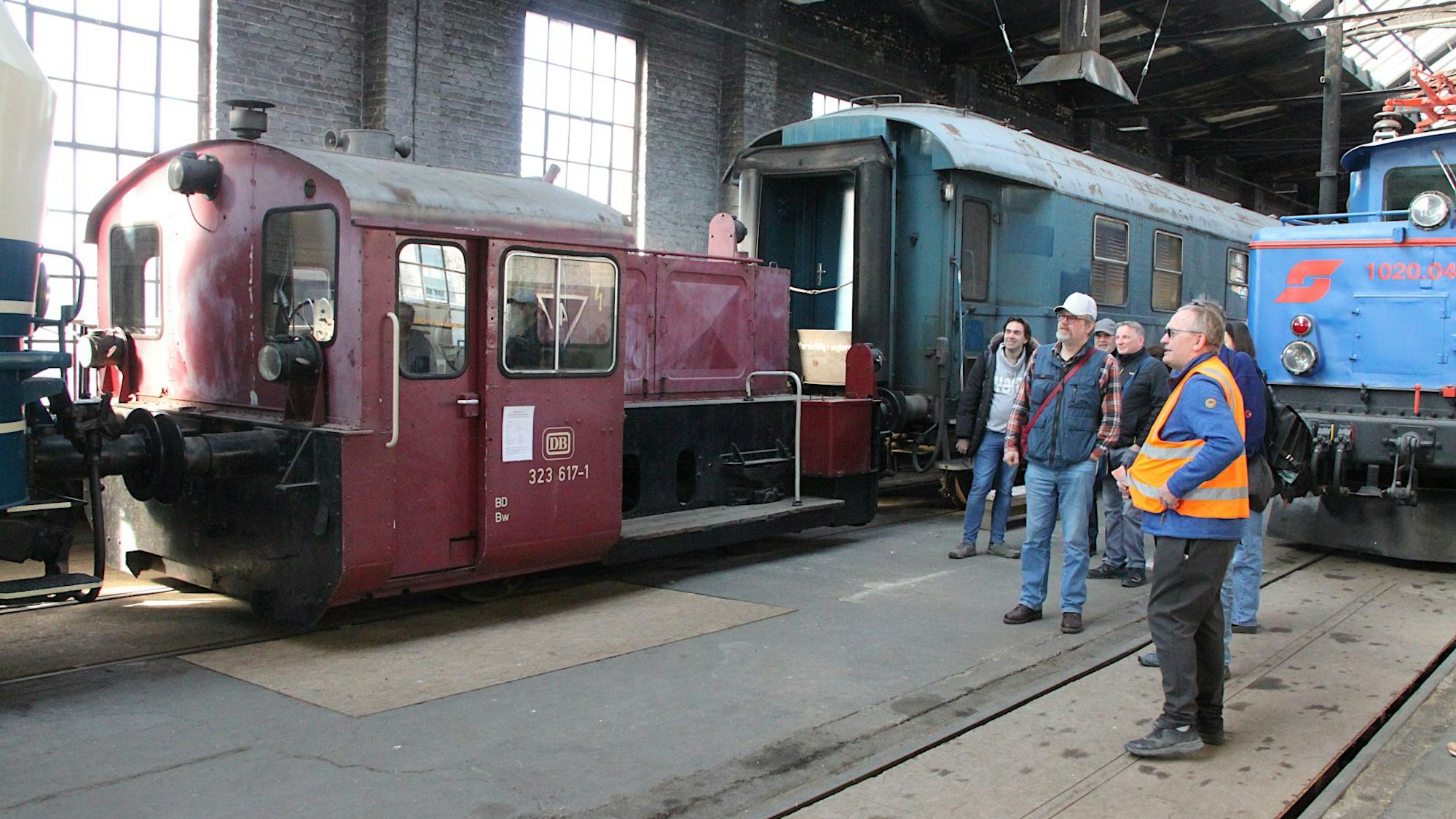 Ein Gruppe Menschen steht an einem alten Eisenbahnwaggong.