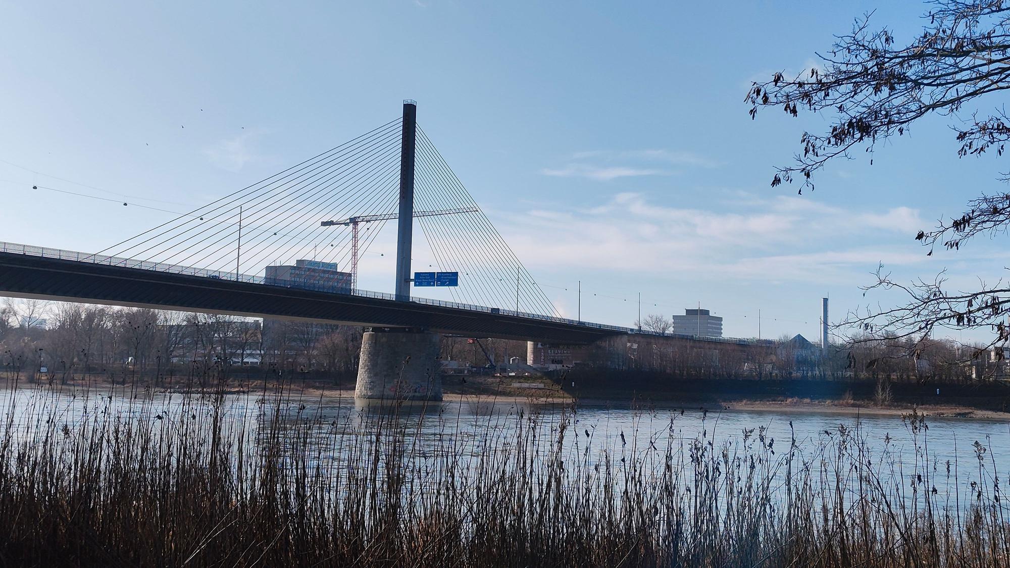 Die Nordbrücke vom rechten Rheinufer aus, mit einem Kran im Hintergrund.