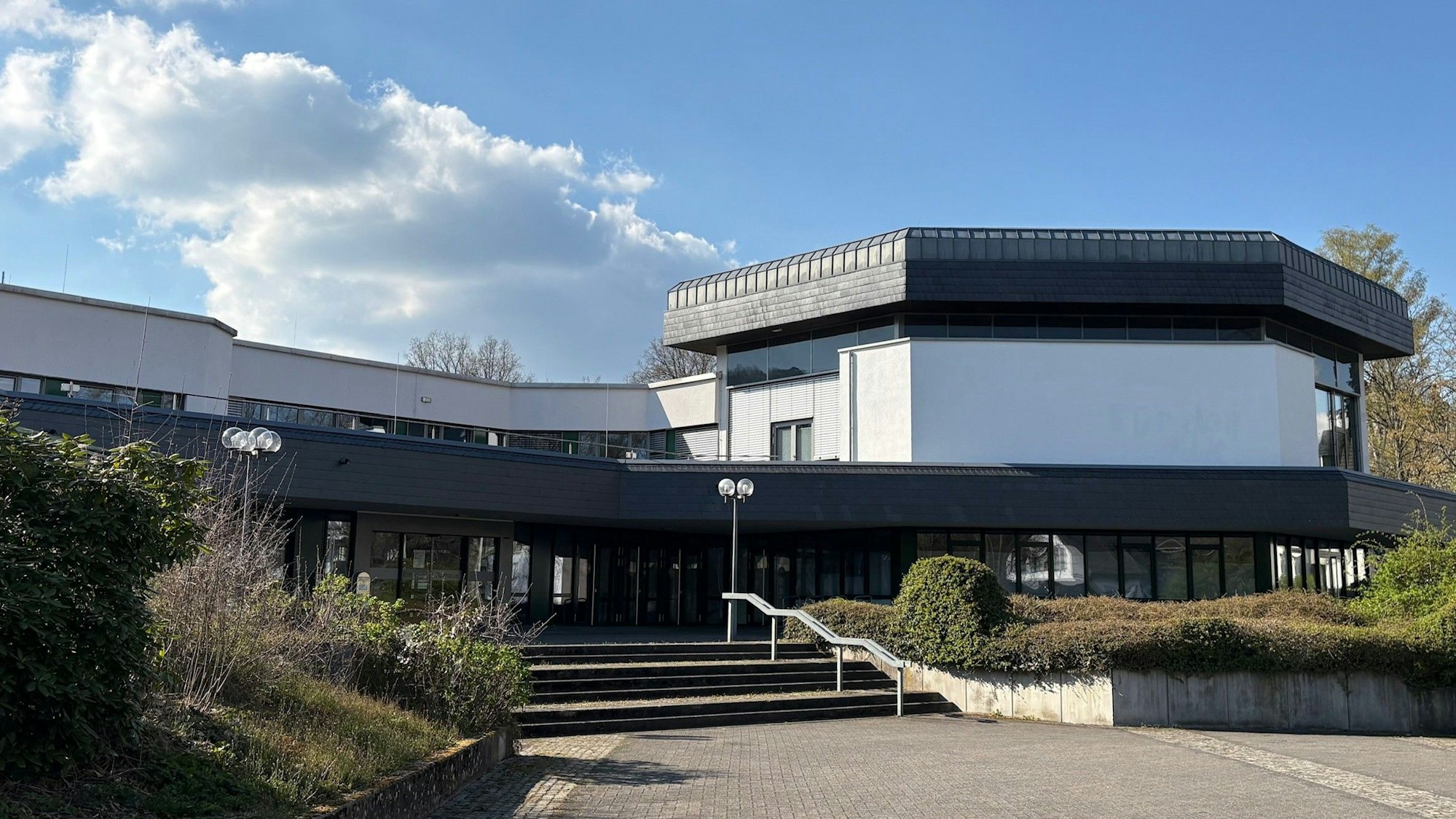 Das Foto zeigt das Rathaus der Gemeinde Reichshof in Denklingen samt Vorplatz an einem sonnigen Nachmittag.