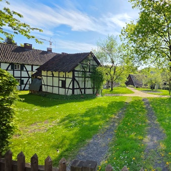 Rund um eine grüne Wiese stehen Fachwerkhäuser.