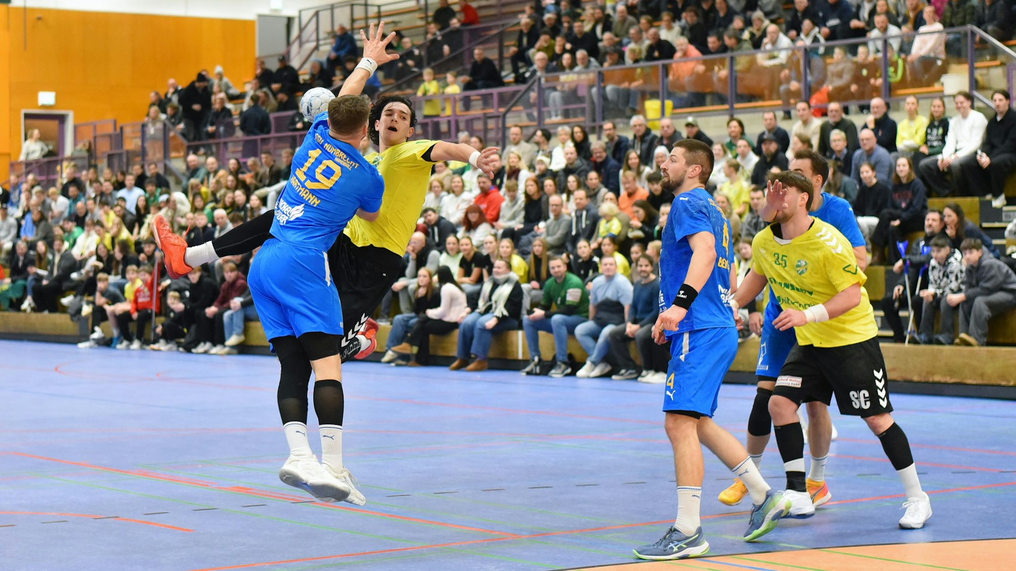 Ein Strombacher springt zum Wurf, während ein Nümbrechter Gegenspieler ihn in der Luft blockt.