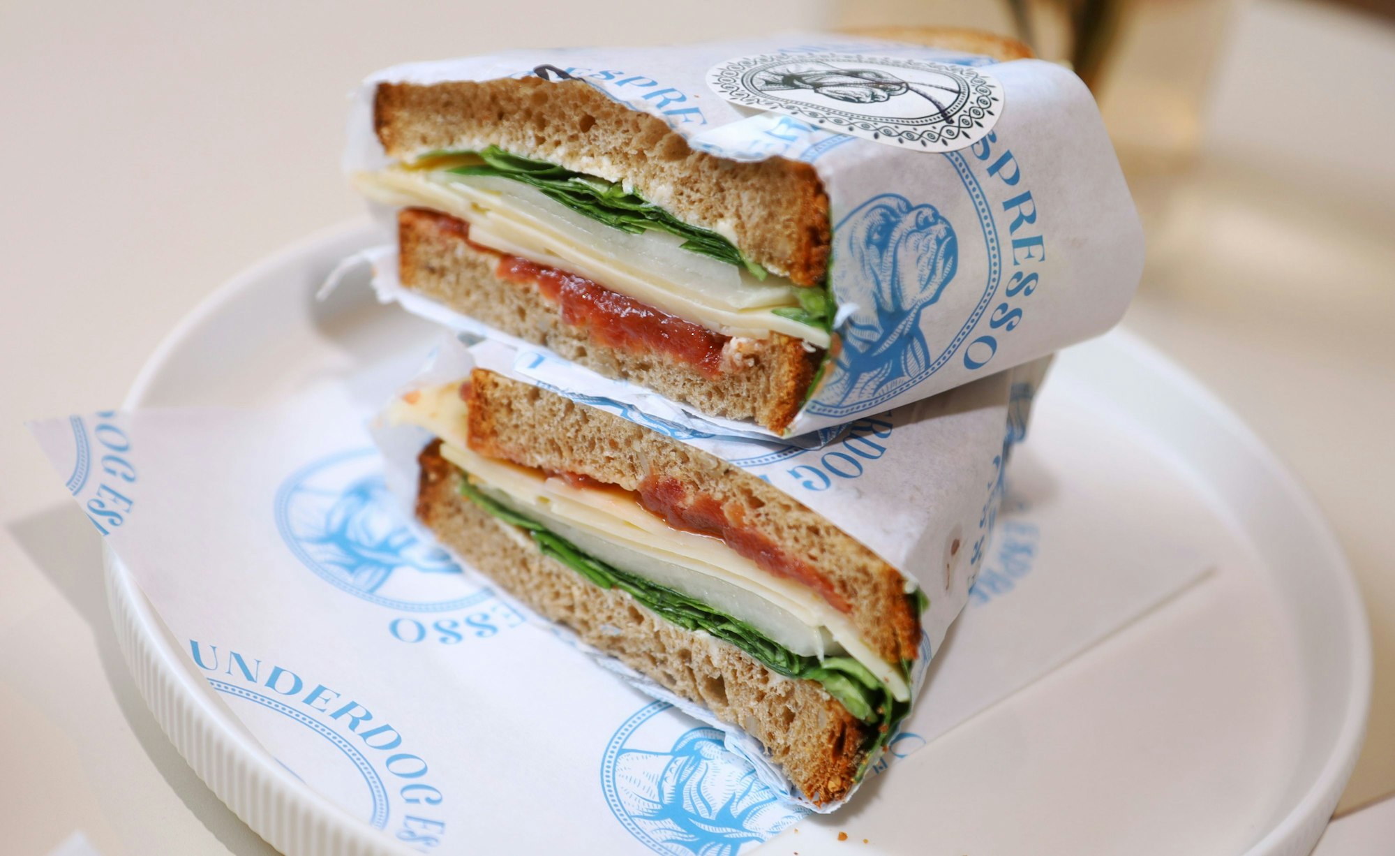 Ein üppig belegtes Sanwiche liegt in zwei Teilen gestapelt auf einem Teller.