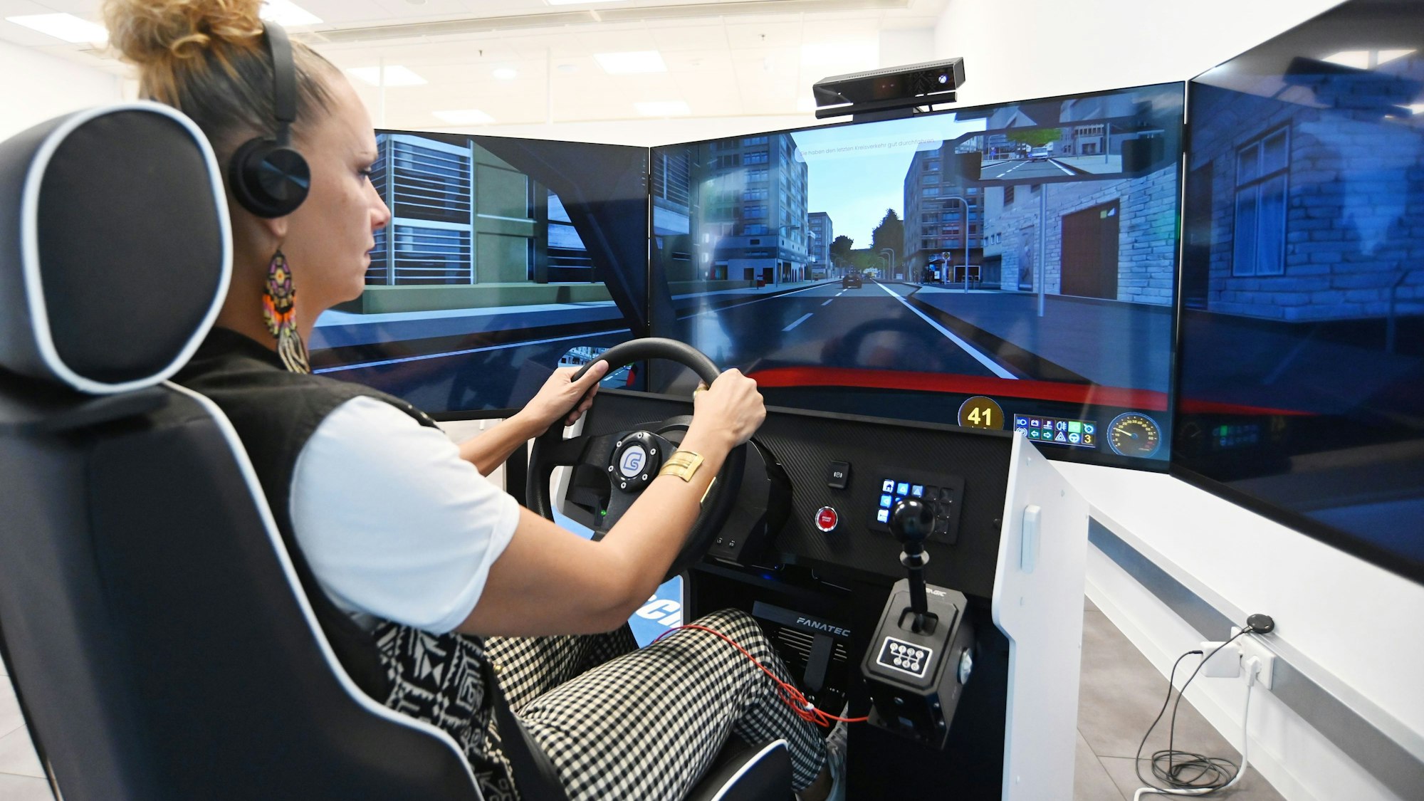 Eine Fahrschülerin übt an einem Fahrsimulator.
