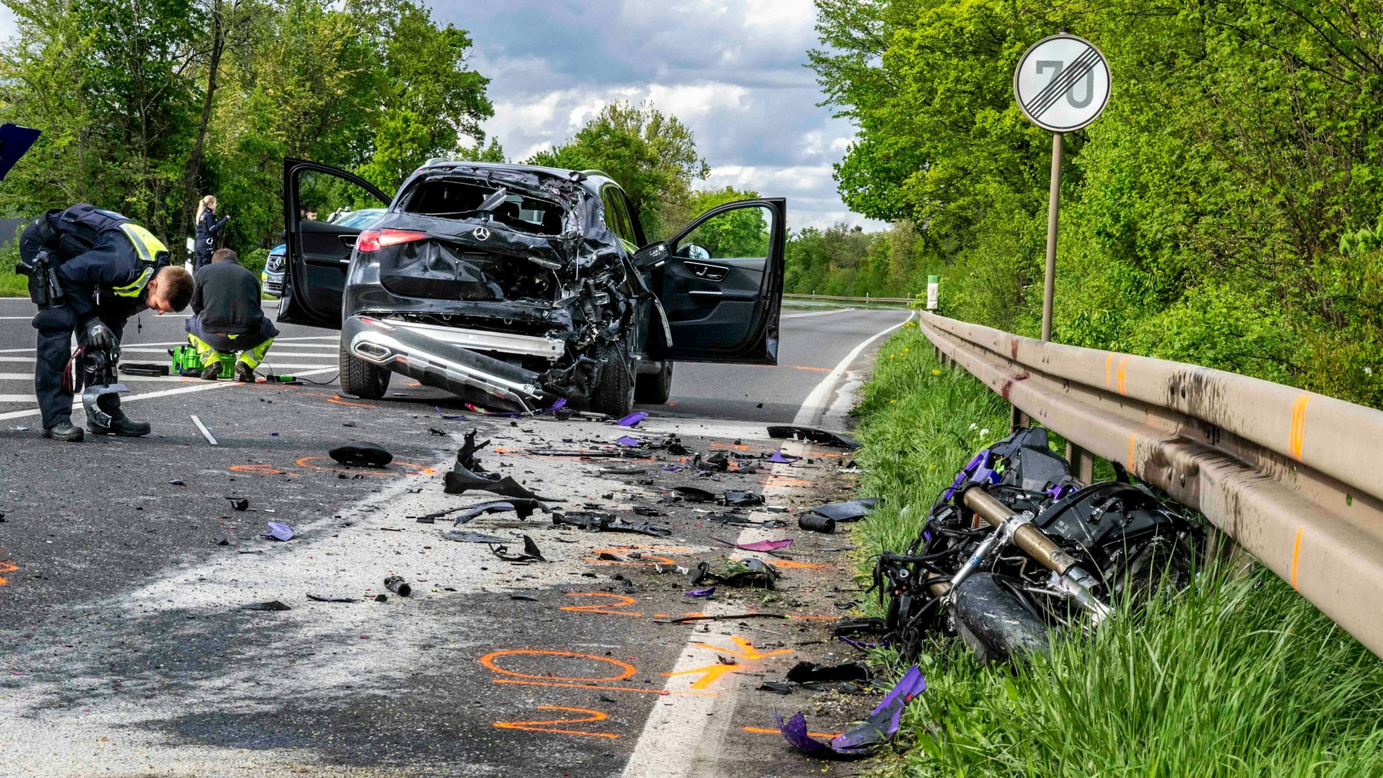 Das Bild zeigt den Unfall. Sowohl der Mercedes SUV als auch das Krad sind stark beschädigt. Die Polizei ist bei der Unfallaufnahme.