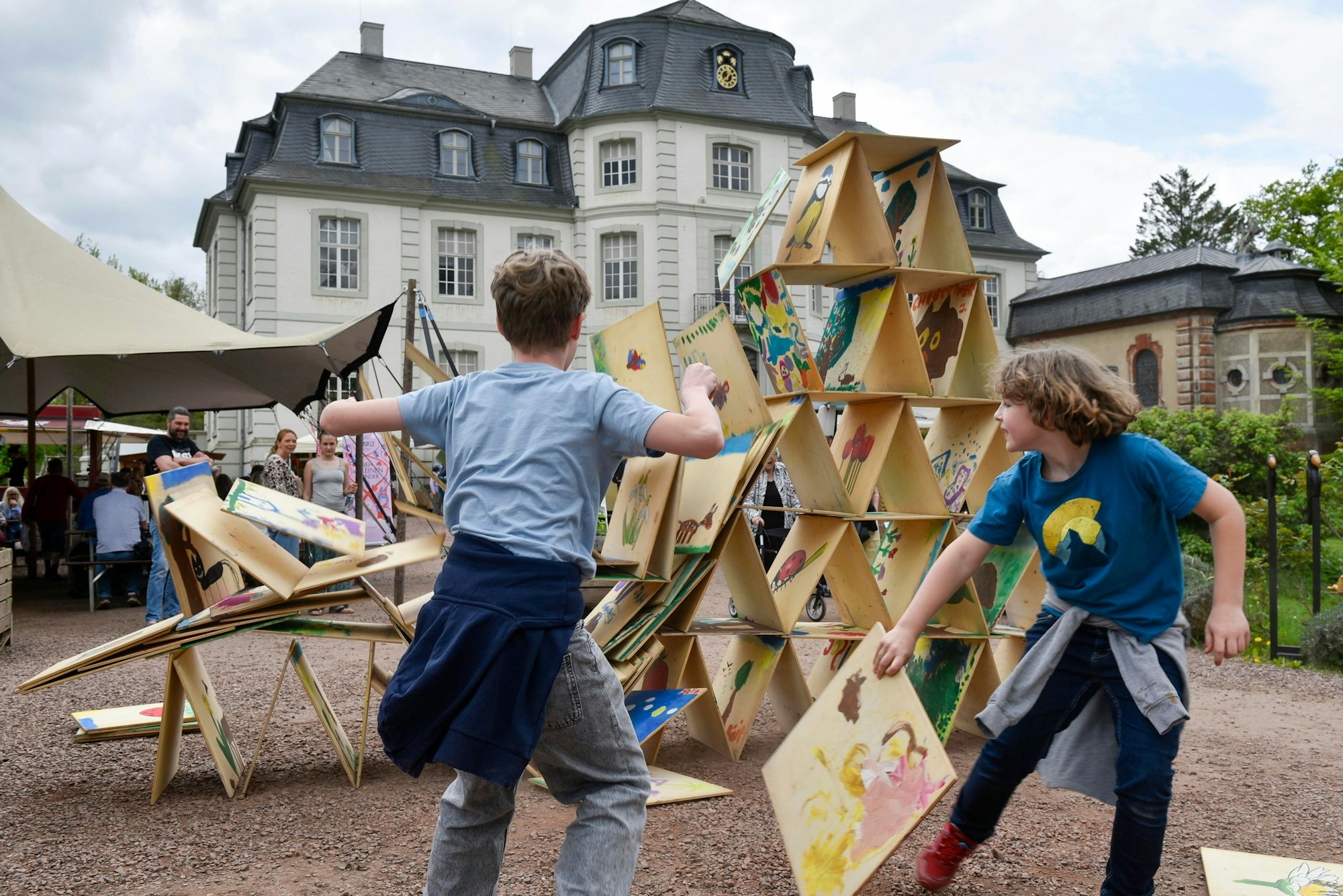 Auf dem Bild sind die beiden Jungen zu sehen, die das große Kartenhaus zum Einsturz bringen.
