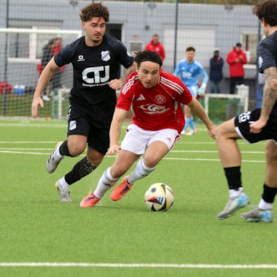 Marlon Große führt den Ball in gebückter Haltung zwischen zwei Gegenspielern hindurch.