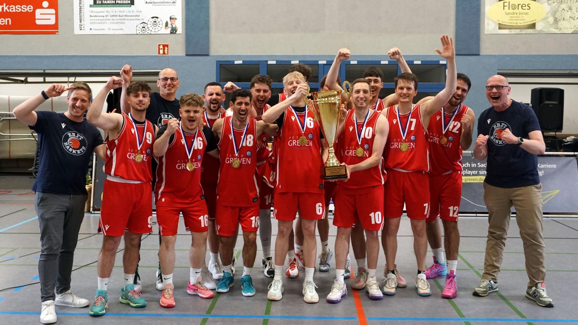 Die Erftbaskets Bad Münstereifel jubeln mit Landrat und Bürgermeister, zwei Spieler halten einen Pokal in die Höhe.