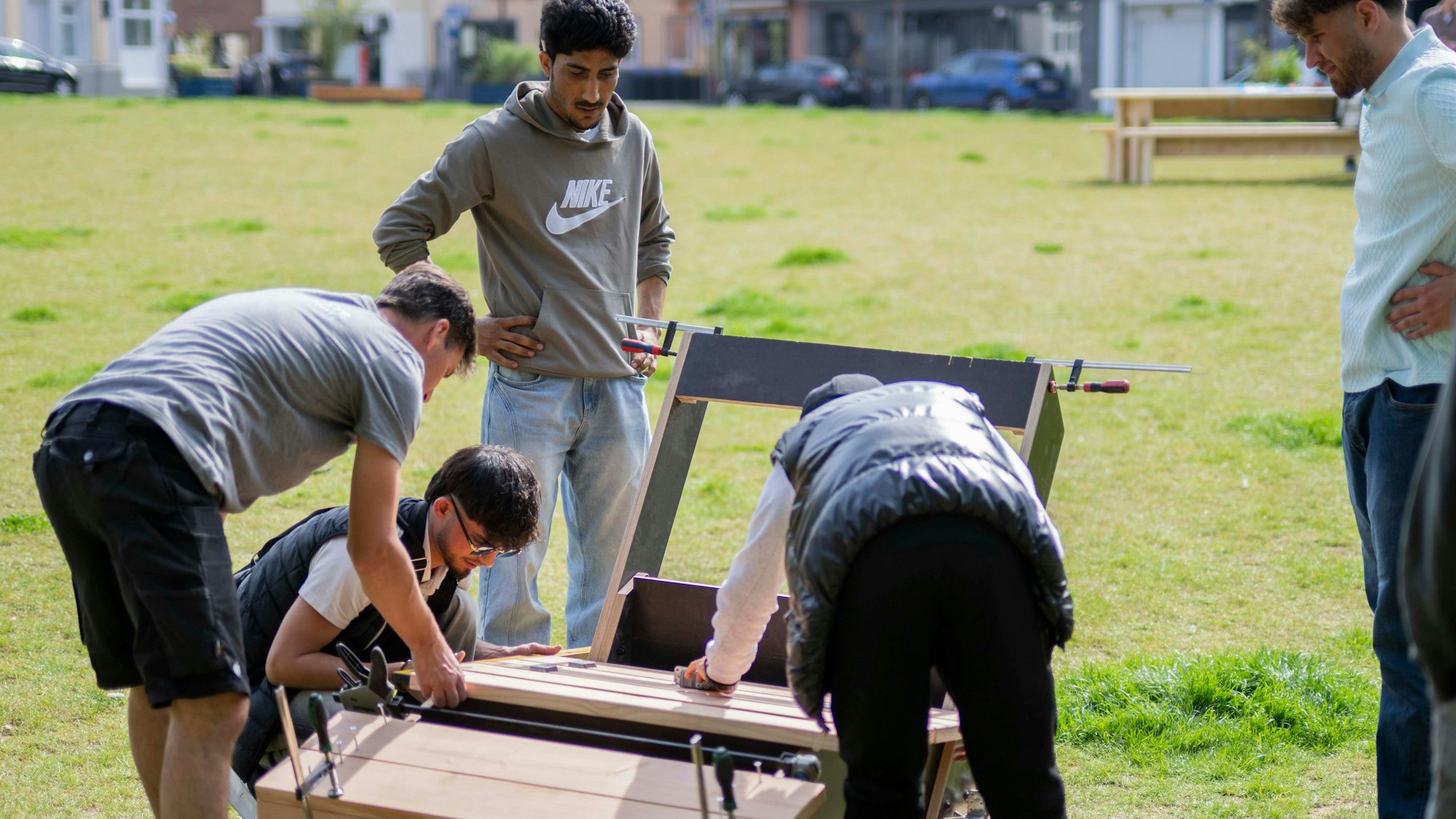 Das Bild zeigt einige junge Erwachsene, die auf Holz eine Sitzgelegenheit bauen.