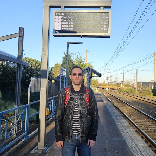 Das Bild zeigt den Fahrgast an der Haltestelle, die Gleise neben sich.