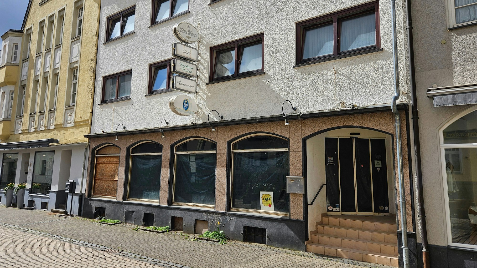 Blick auf ein leerstehendes Ladenlokal, dessen Fenster von ihnen abgeklebt sind.