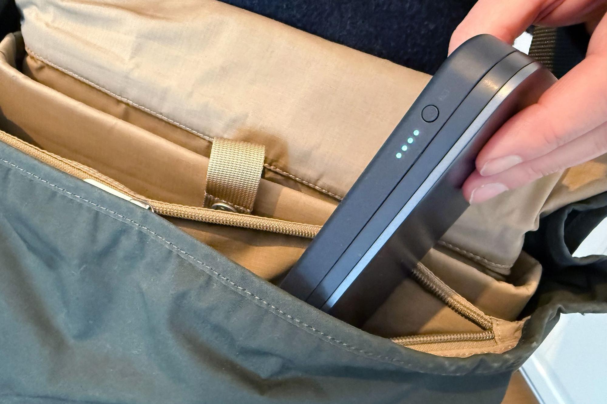 Mann steckt eine Powerbank in seinen Rucksack