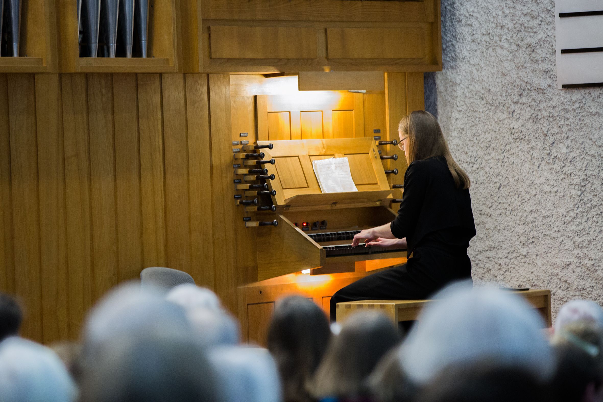 Eine Frau mit langem blonden Haar sitzt an einer Kirchenorgel.