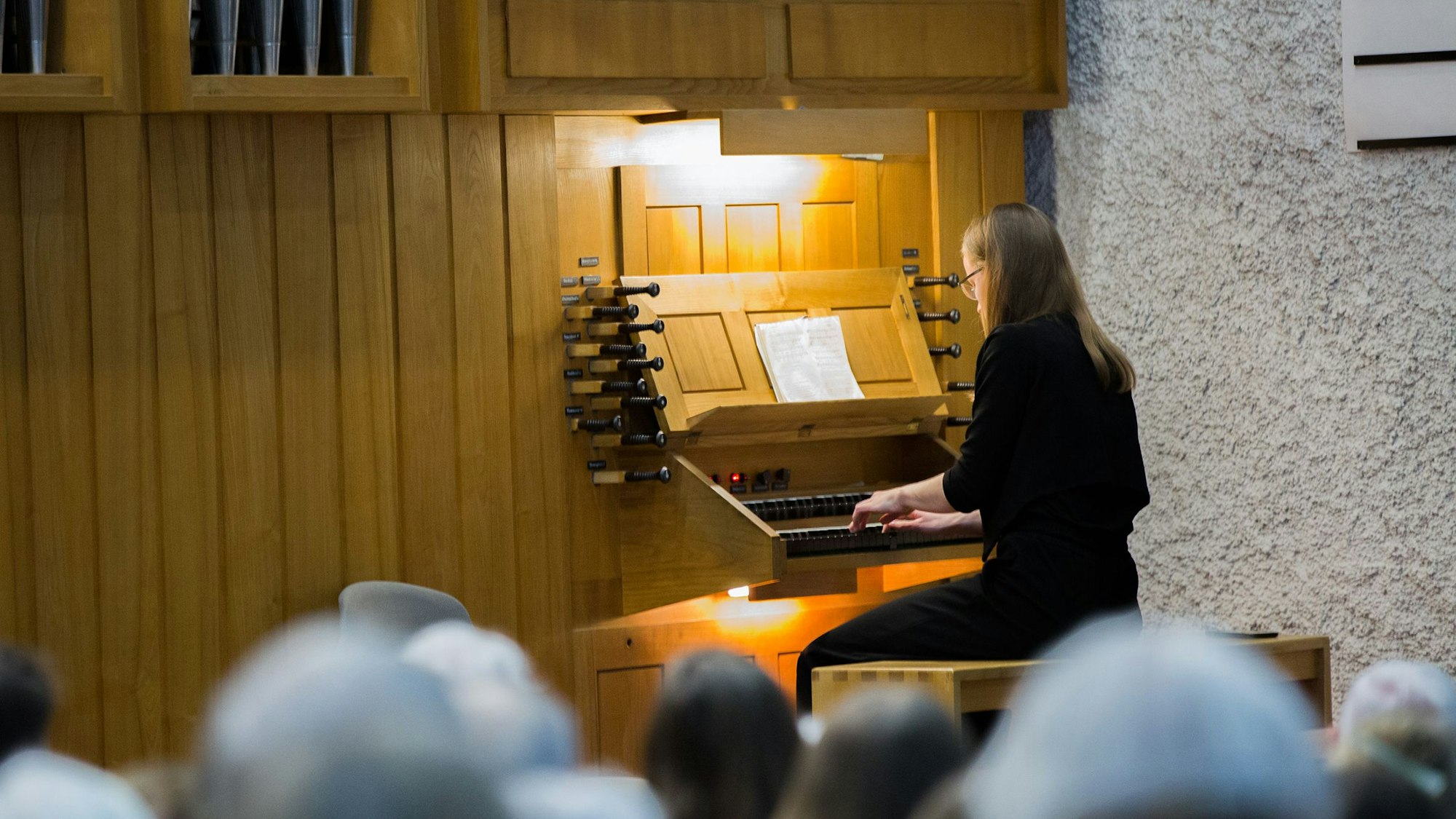 Eine Frau mit langem blonden Haar sitzt an einer Kirchenorgel.